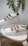 Sneakers blanches et rose poudré mises en valeur dans un décor minimaliste