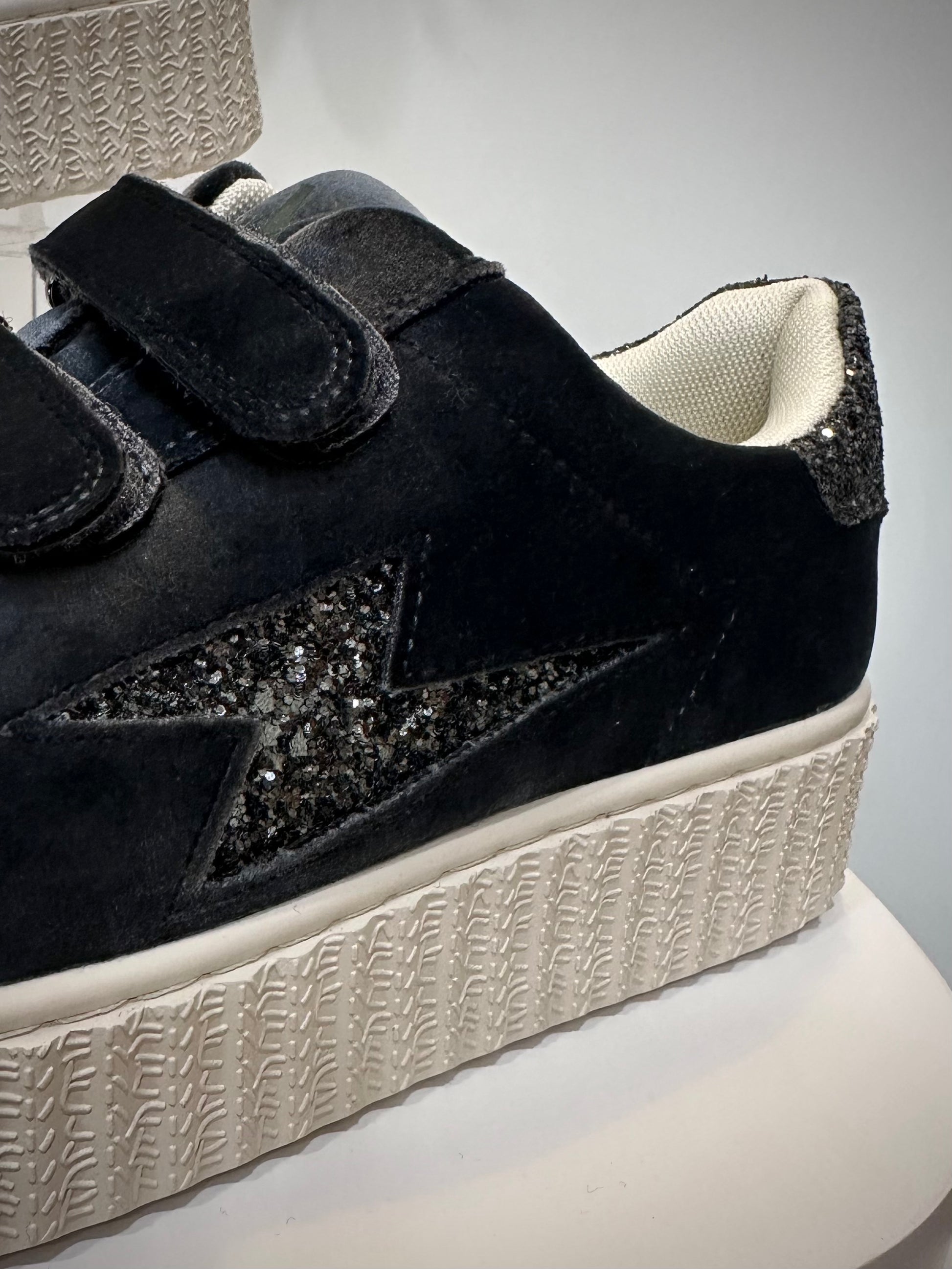 Gros plan sur la découpe éclair pailletée noir et argent des Baskets Billie