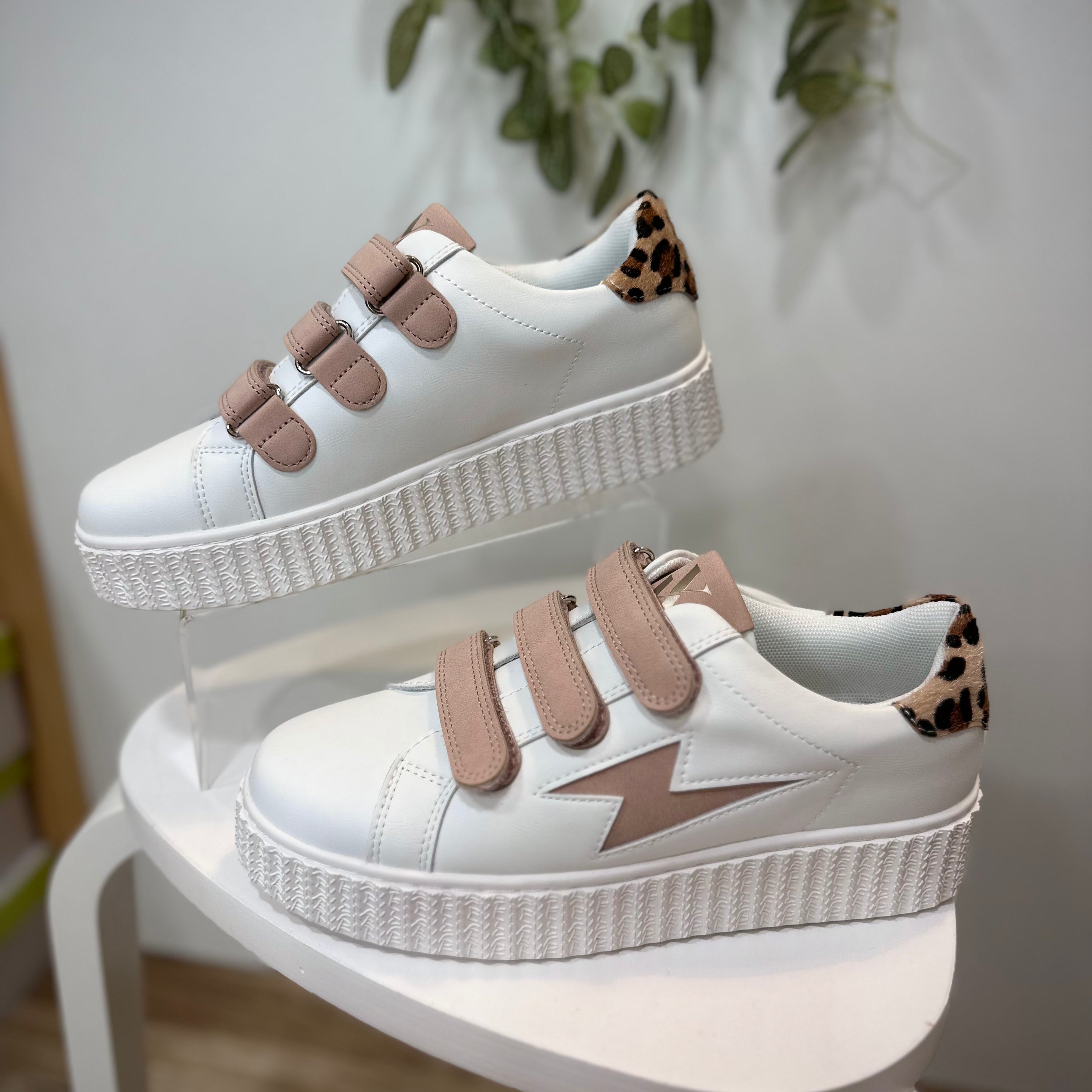Sneakers blanches et rose poudré mises en valeur dans un décor minimaliste