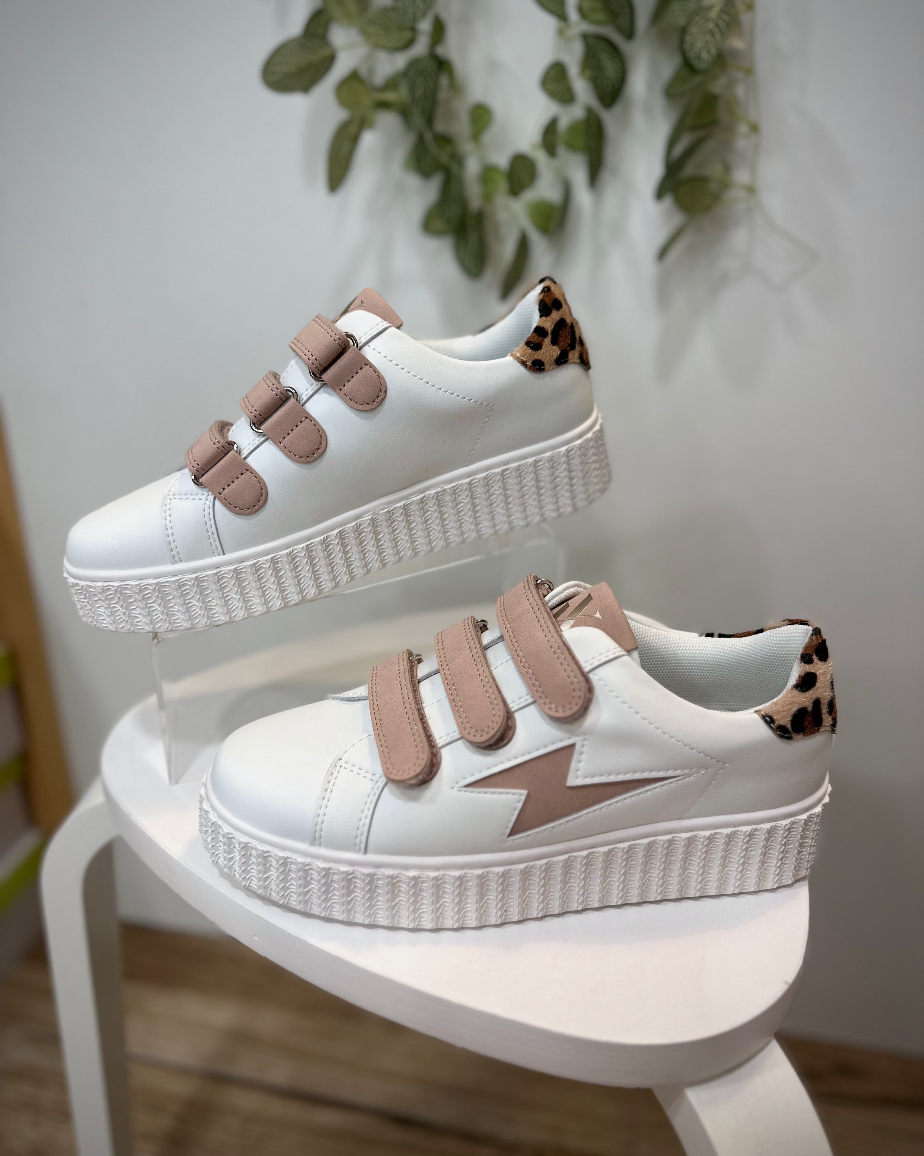 Sneakers blanches et rose poudré mises en valeur dans un décor minimaliste