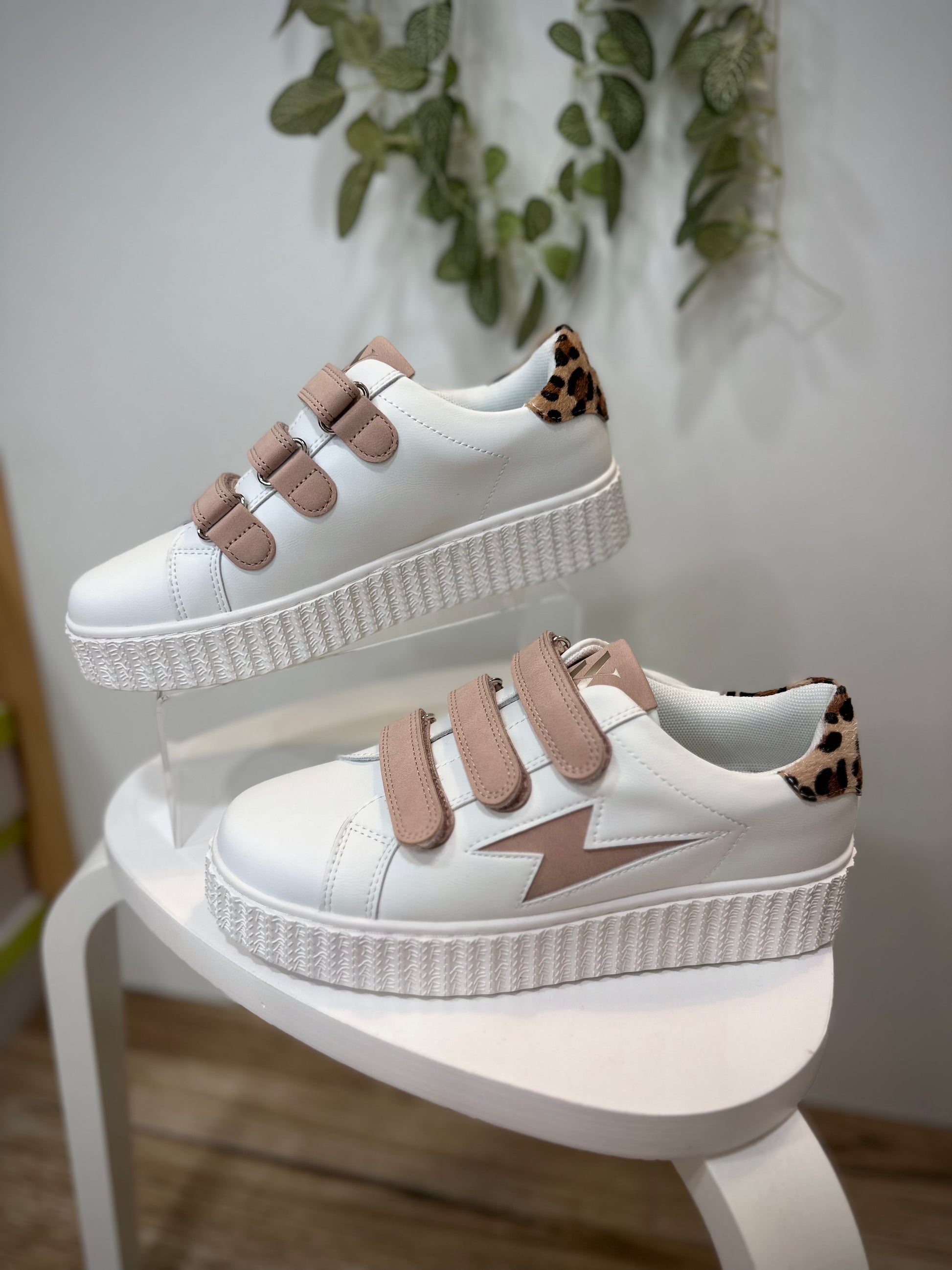 Sneakers blanches et rose poudré mises en valeur dans un décor minimaliste