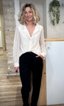 Blouse CLÉOPHÉE en dentelle écrue portée avec un pantalon noir