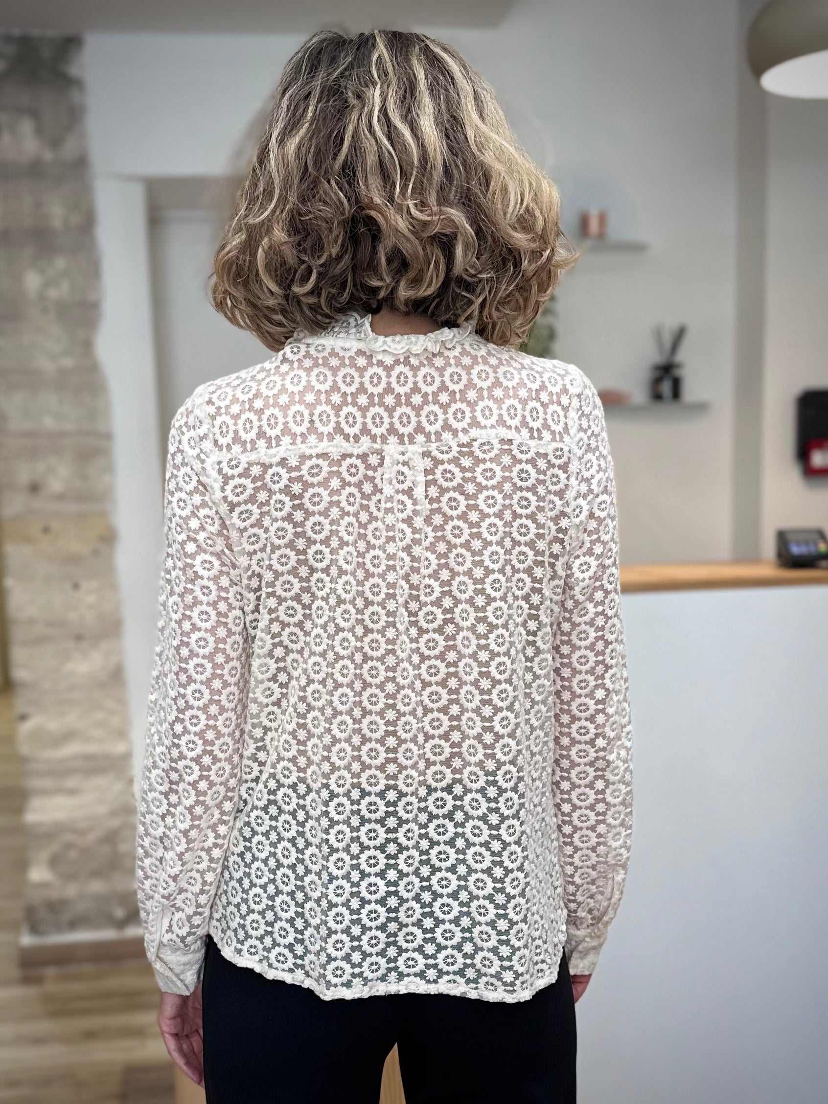 Femme de dos portant une blouse dentelle avec un pantalon noir