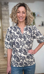 Femme souriante portant blouse imprimée bleu marine 