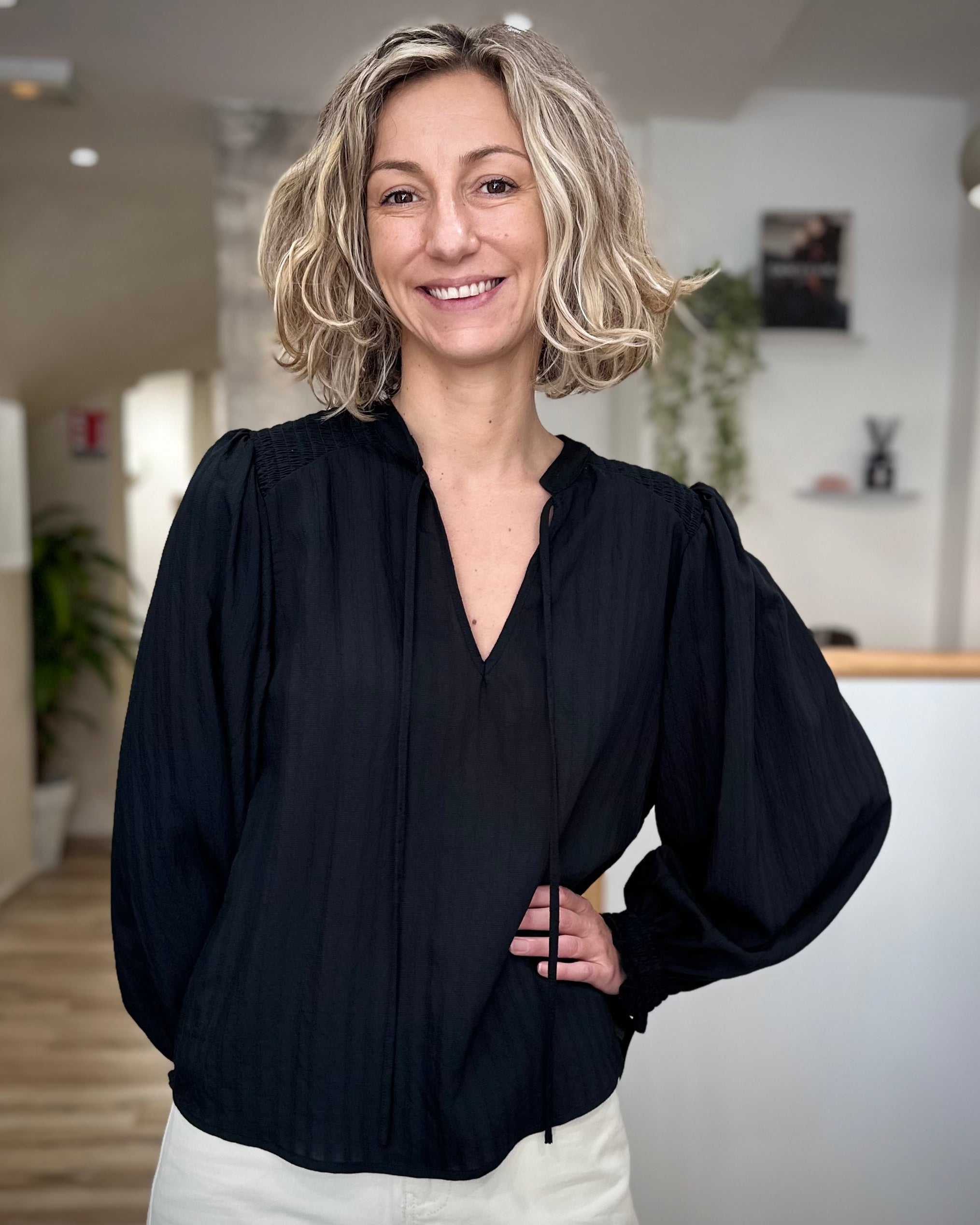 Femme portant une blouse noire fluide à col noué