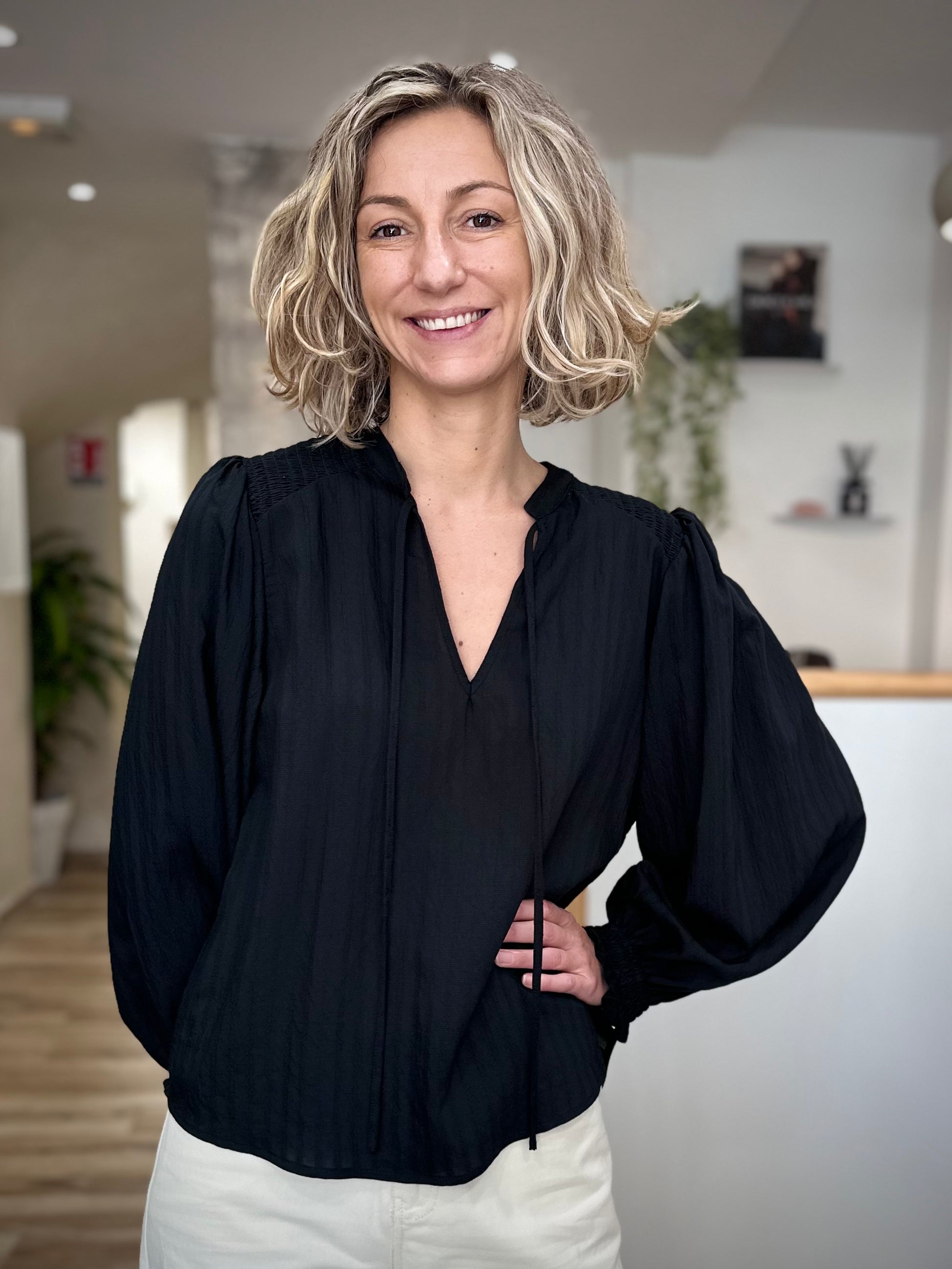 Femme portant une blouse noire fluide à col noué