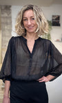 Femme portant une blouse noire transparente en lurex brillante