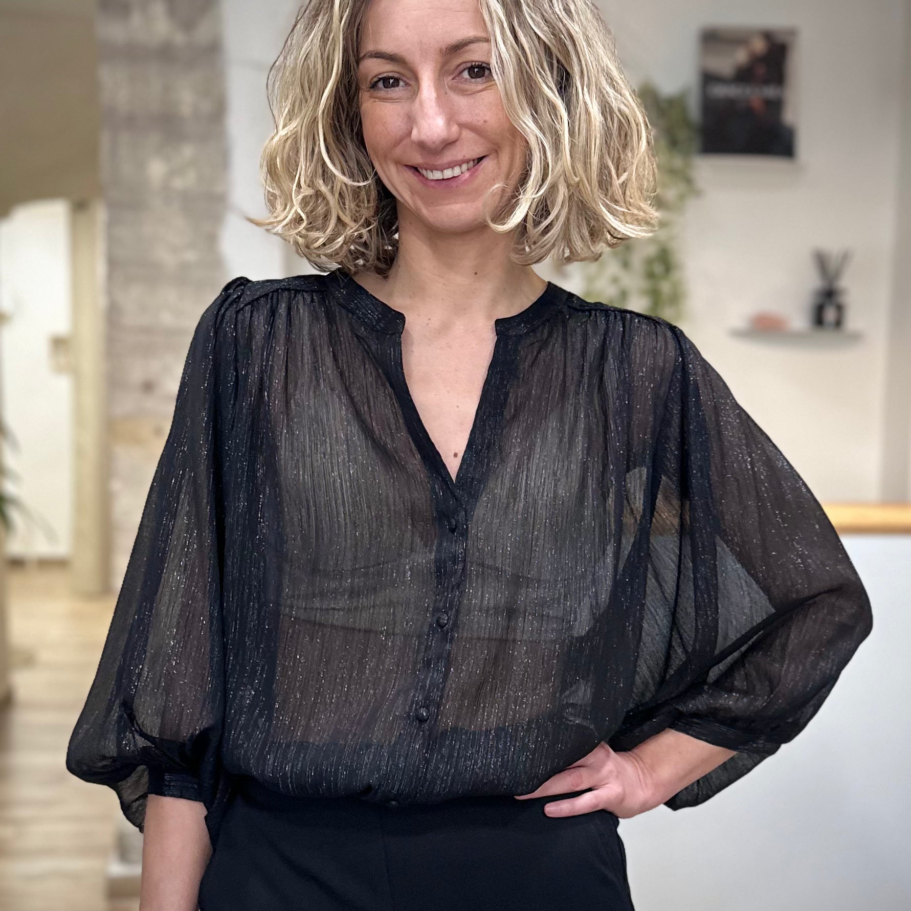 Femme portant une blouse noire transparente en lurex brillante