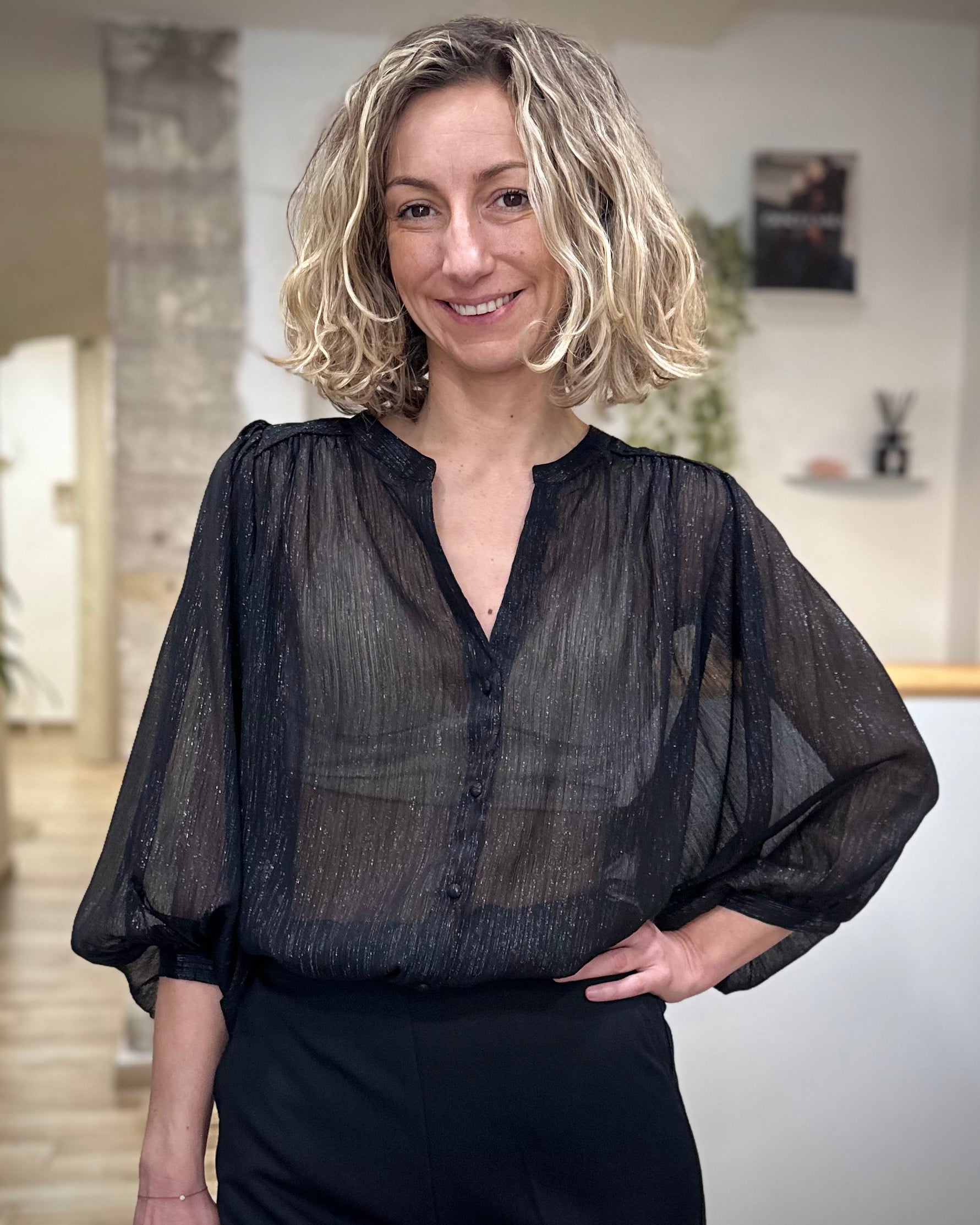 Femme portant une blouse noire transparente en lurex brillante