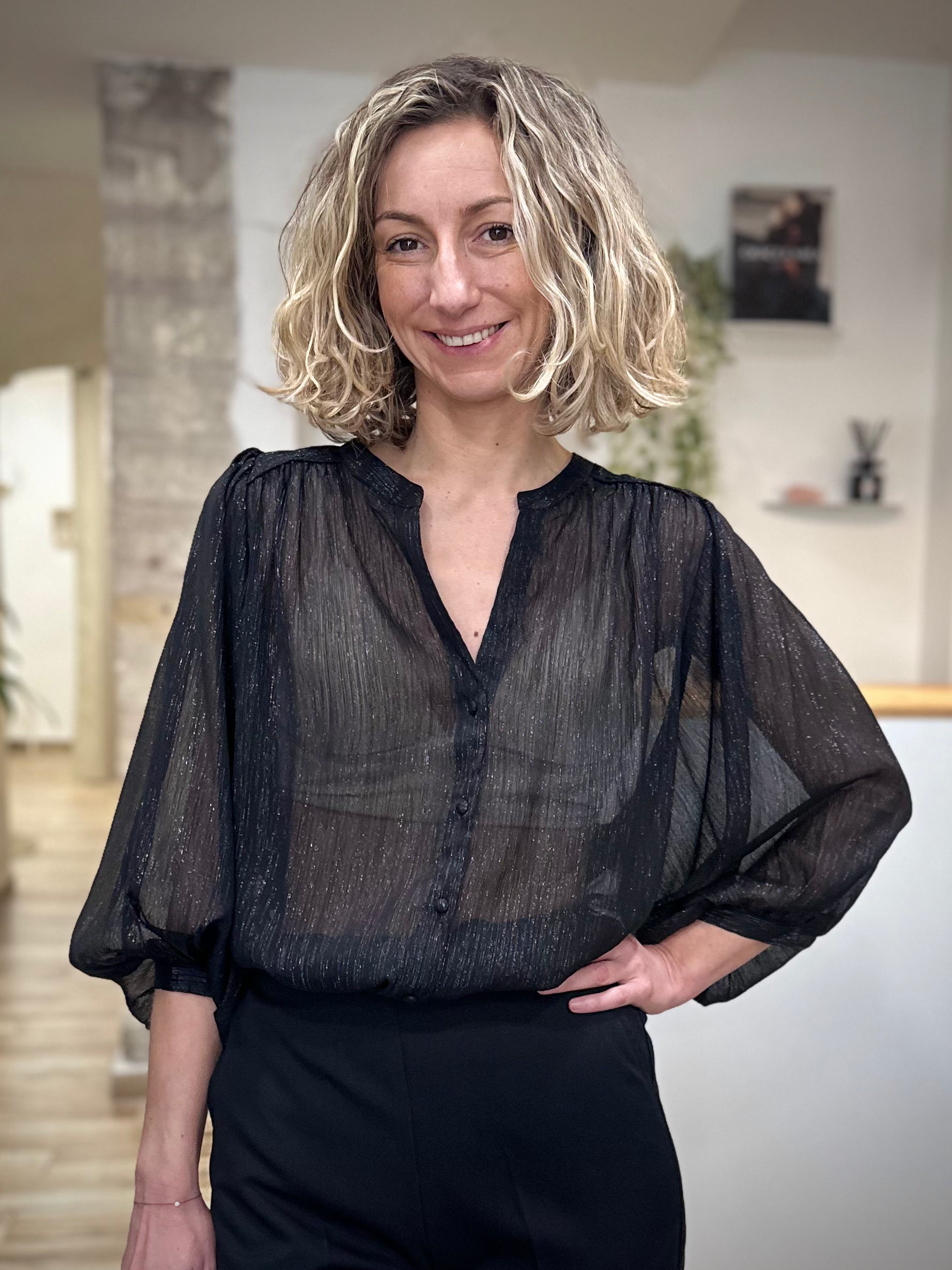 Femme portant une blouse noire transparente en lurex brillante
