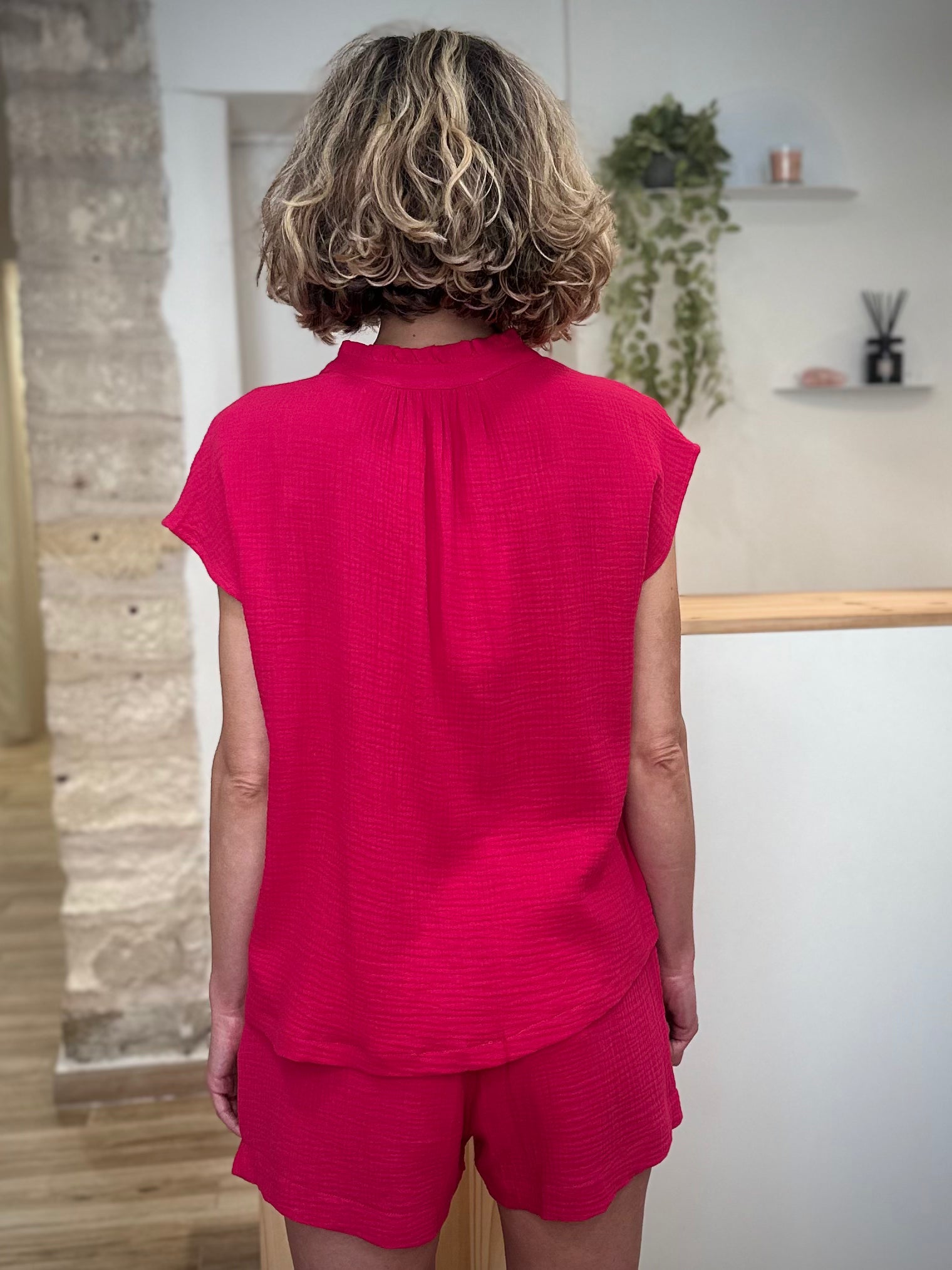 Femme de dos portant une blouse aérienne en gaze de coton fuchsia