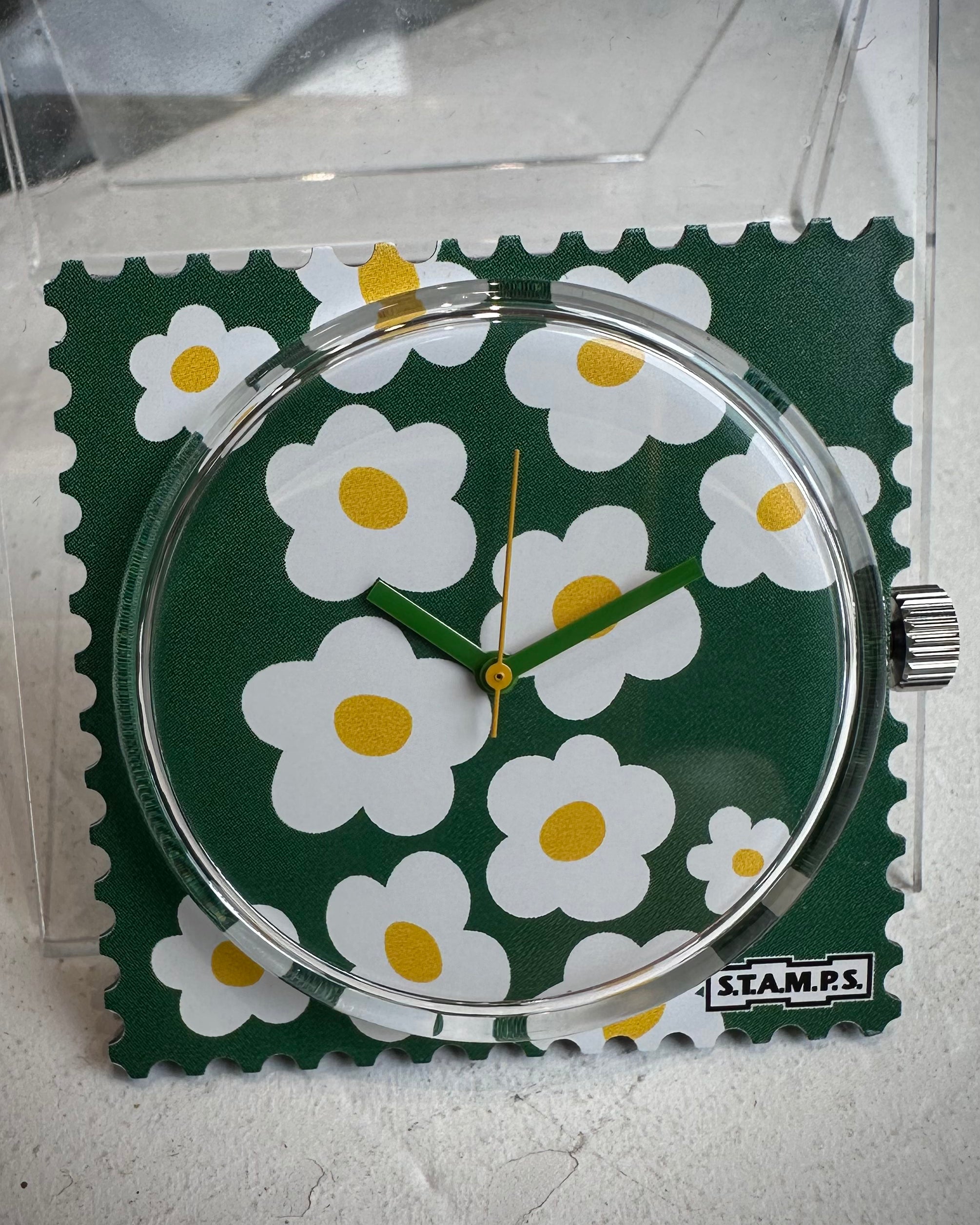 Gros plan cadran STAMPS fleurs blanches fond vert 