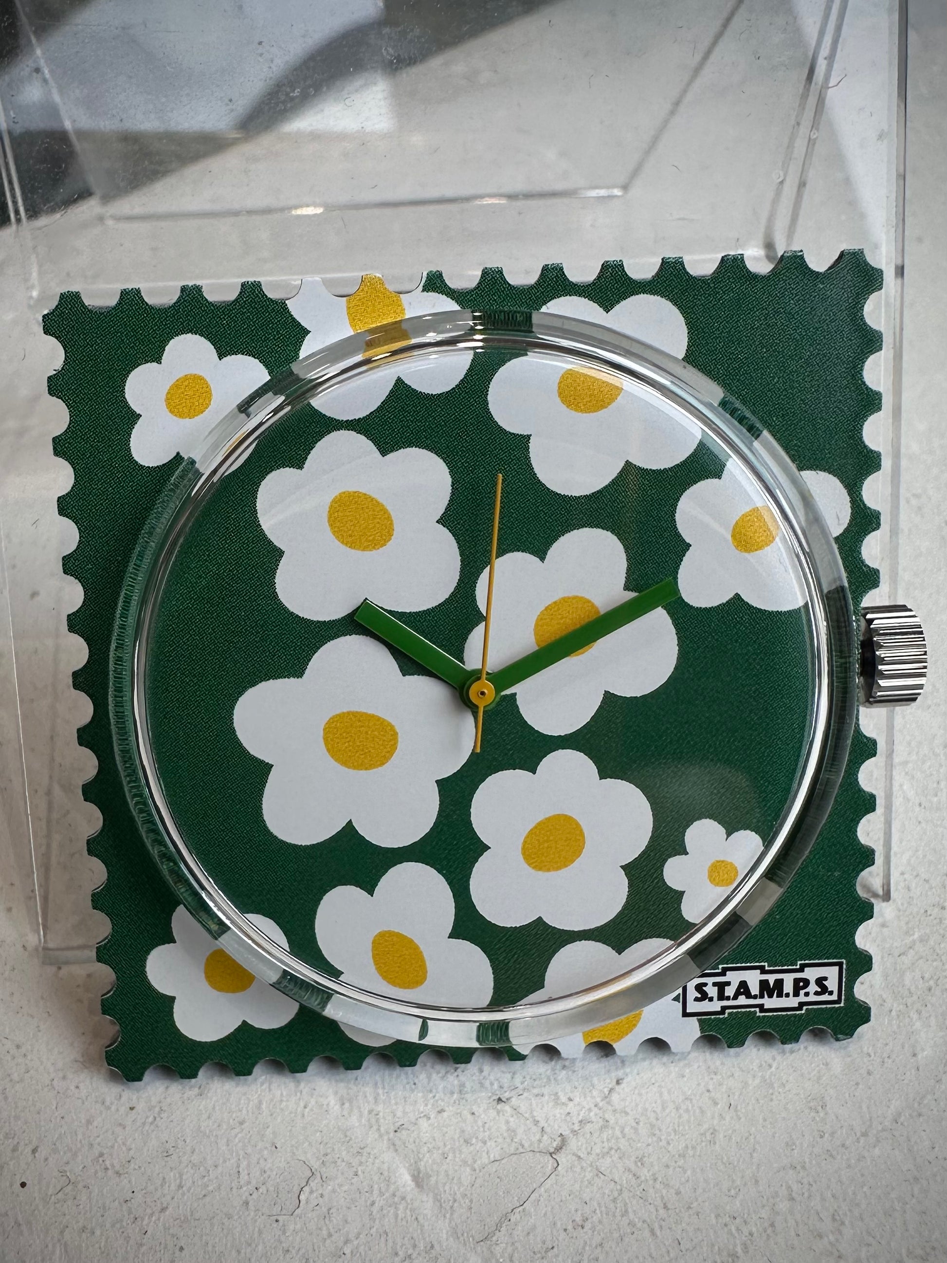 Gros plan cadran STAMPS fleurs blanches fond vert 