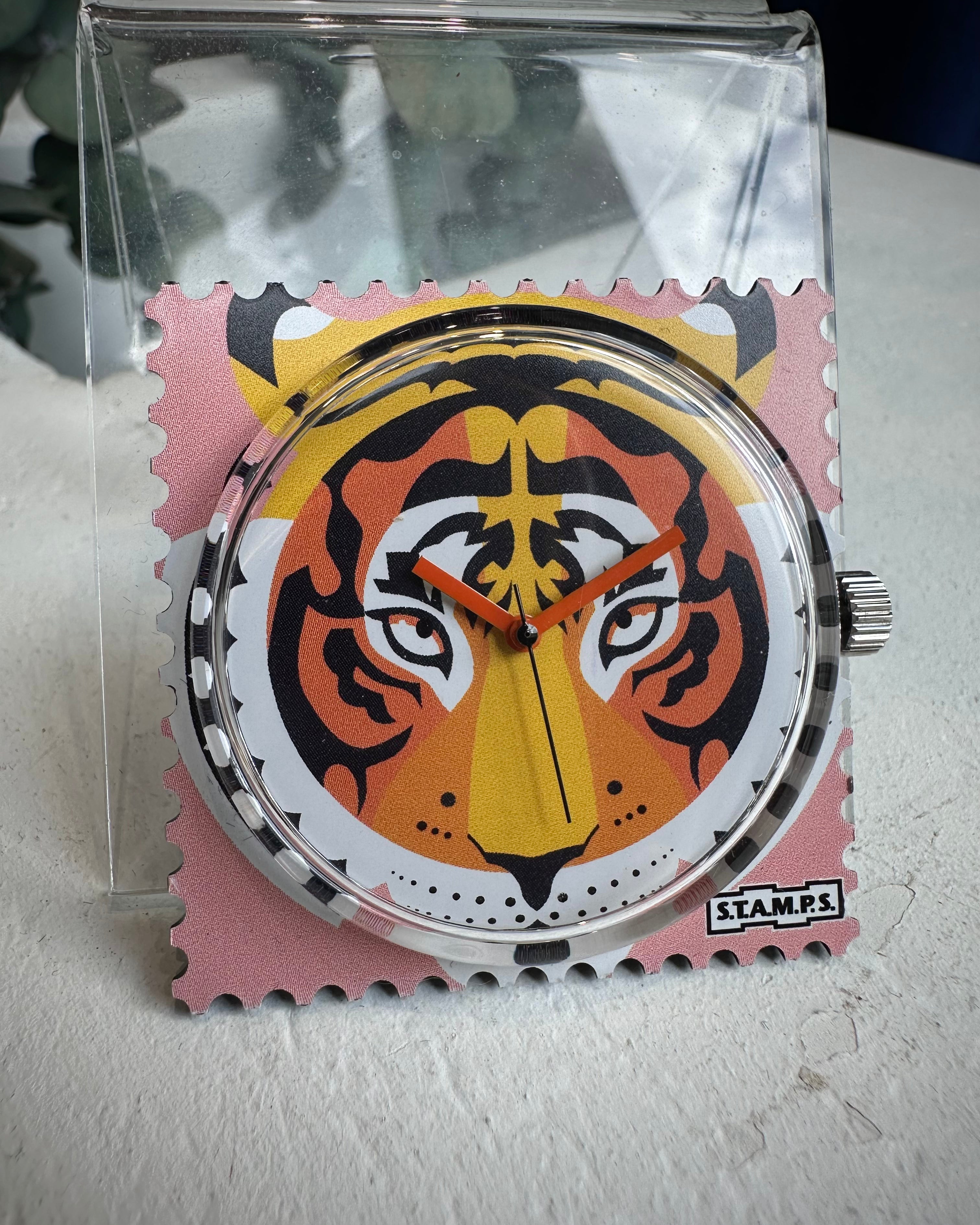 Gros plan cadran STAMPS tigre sur fond rose avec aiguilles orange