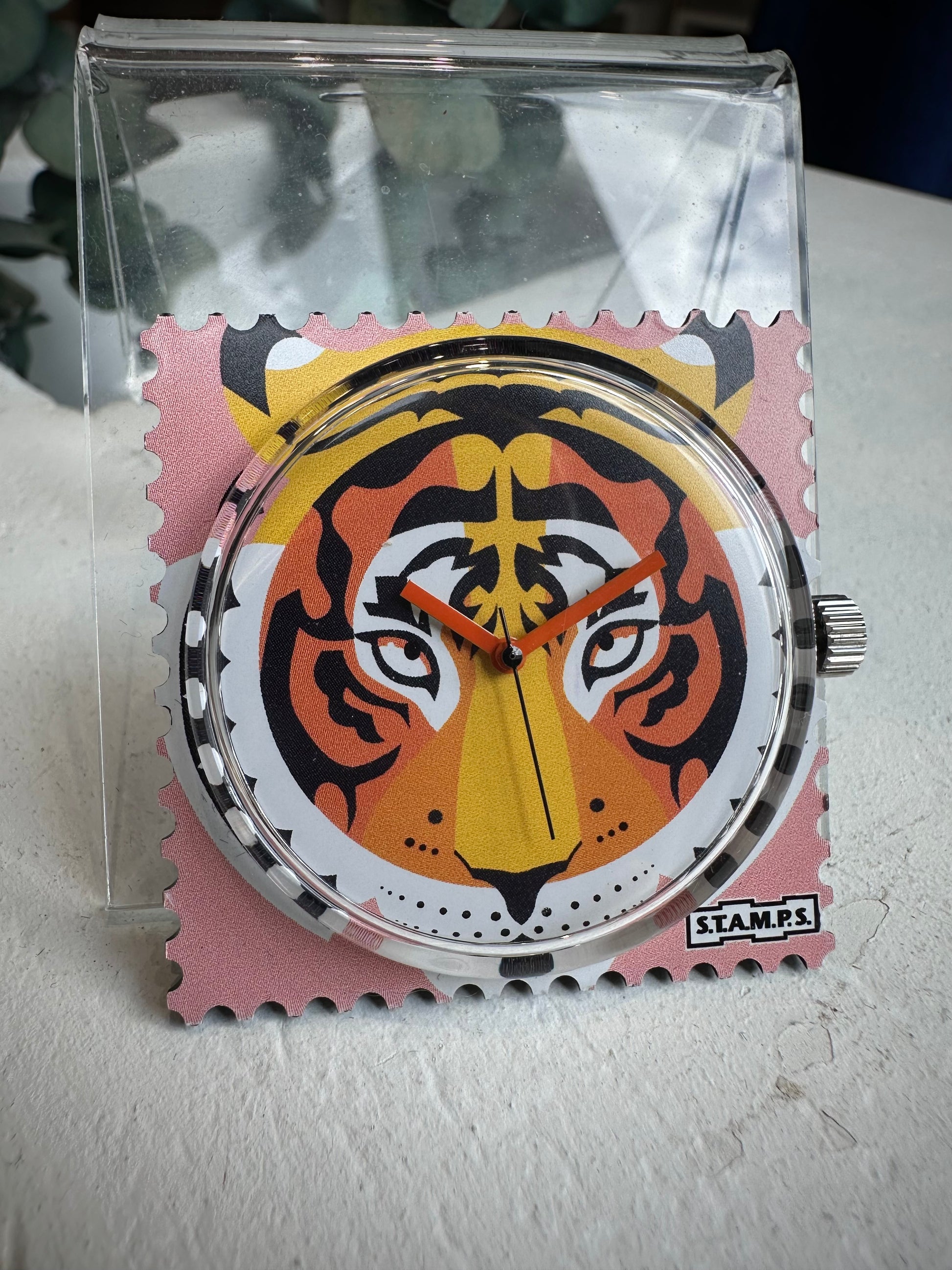 Gros plan cadran STAMPS tigre sur fond rose avec aiguilles orange
