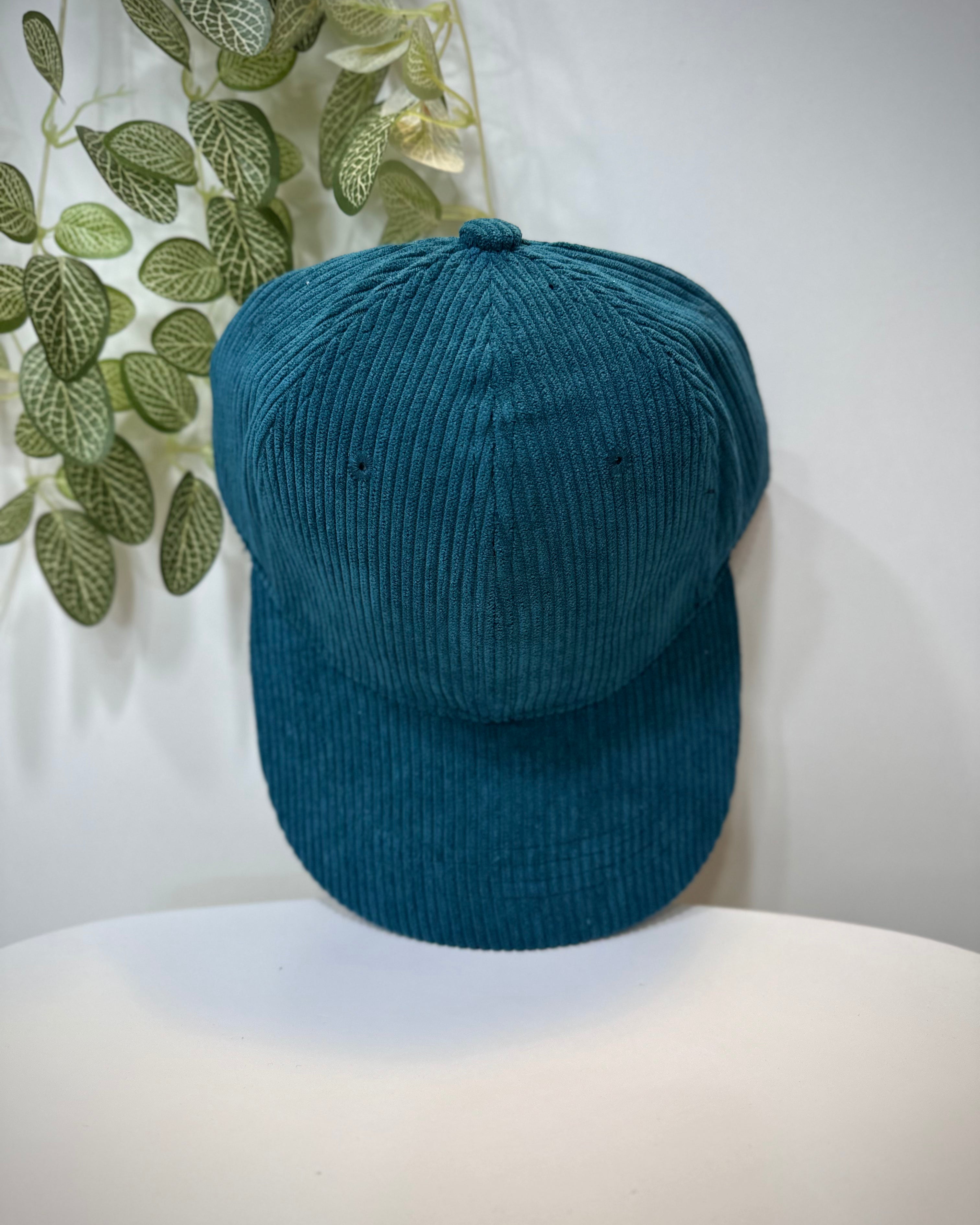 Casquette velours bleu canard posée sur une table 