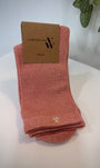 Paire de chaussettes rose saumon scintillantes pliées sur fond clair