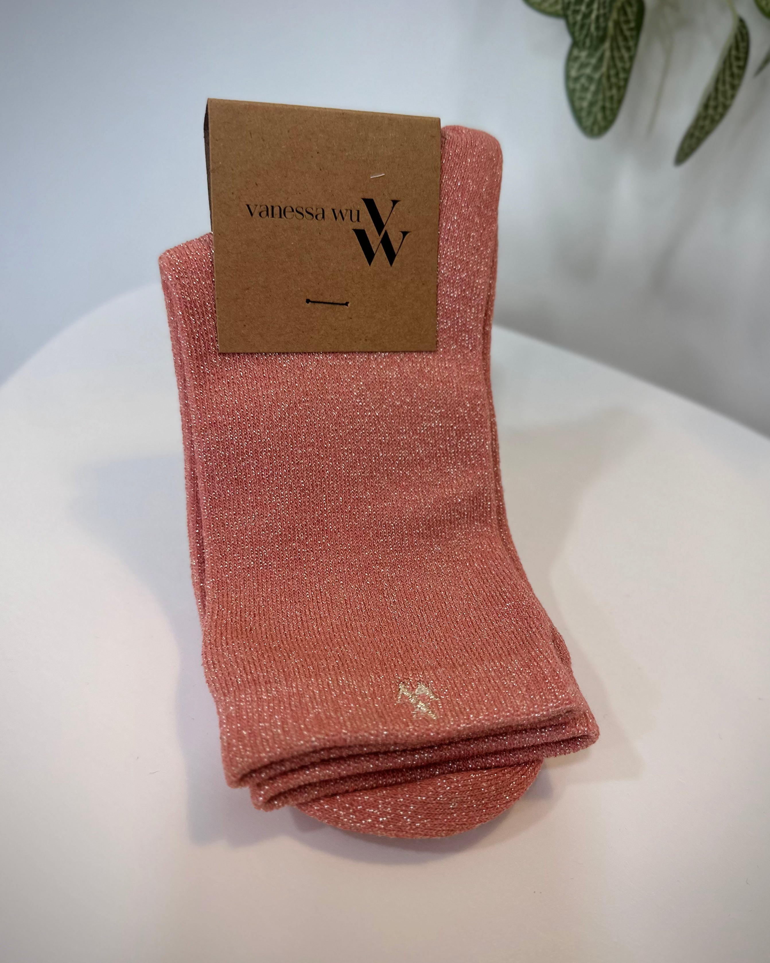 Paire de chaussettes rose saumon scintillantes pliées sur fond clair