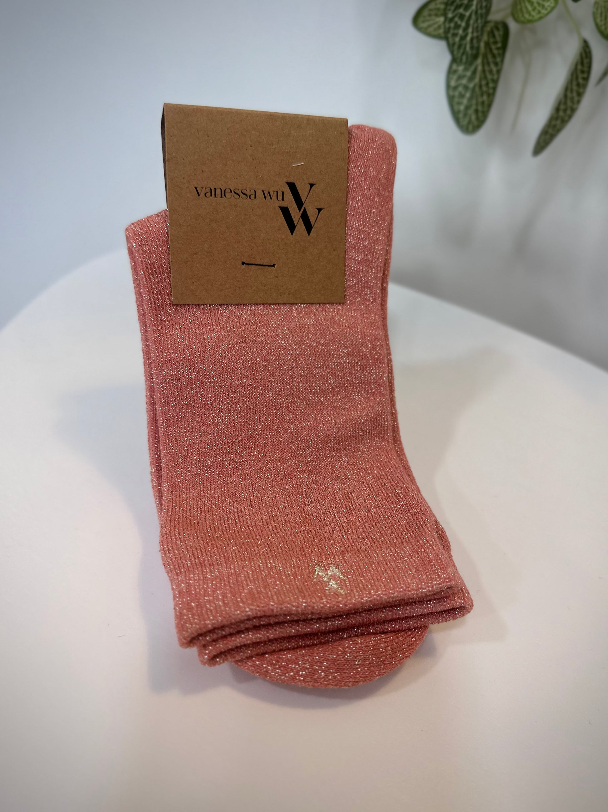 Paire de chaussettes rose saumon scintillantes pliées sur fond clair