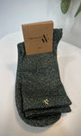 Paire de chaussettes vert foncé scintillantes posée sur fond clair