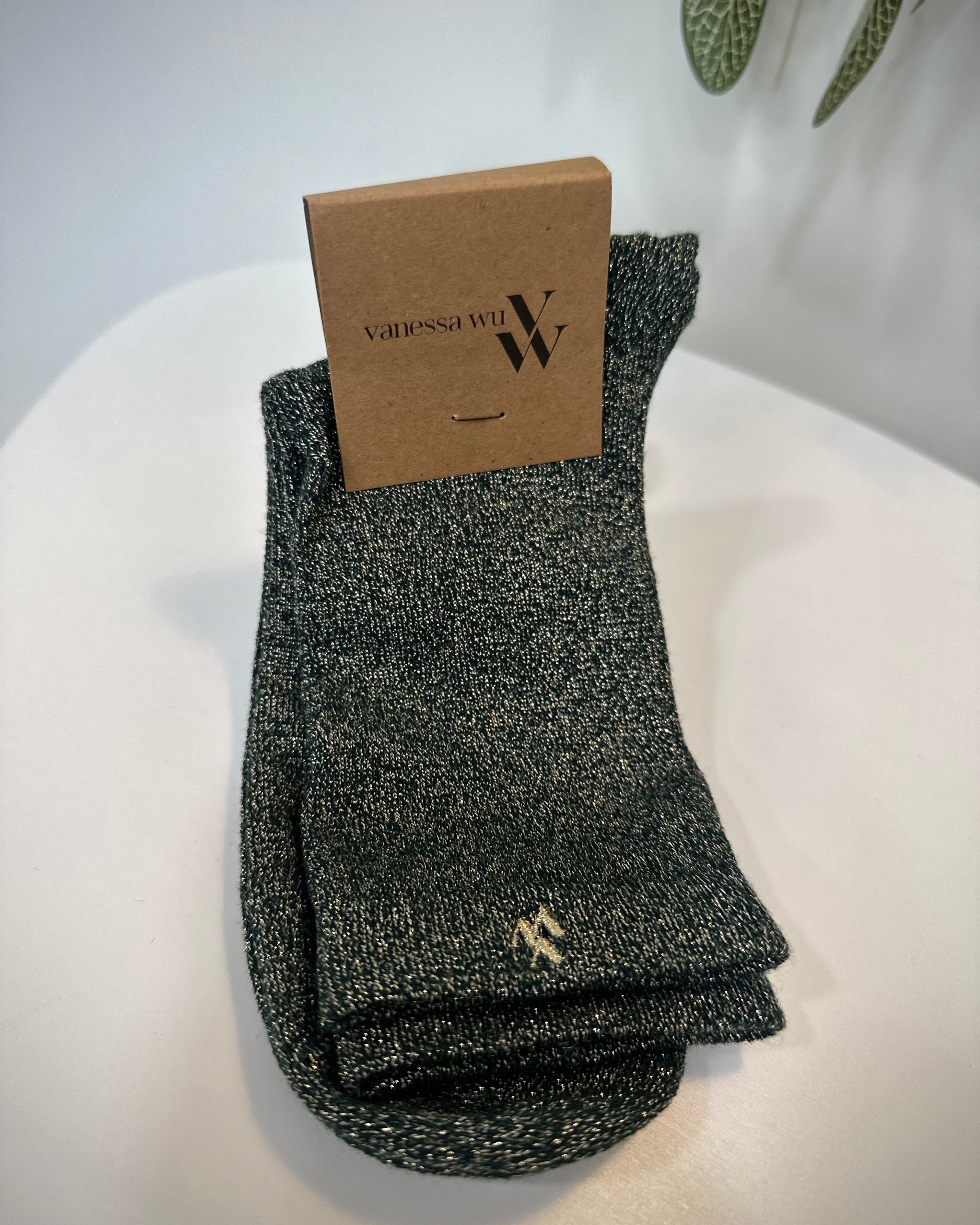 Paire de chaussettes vert foncé scintillantes posée sur fond clair