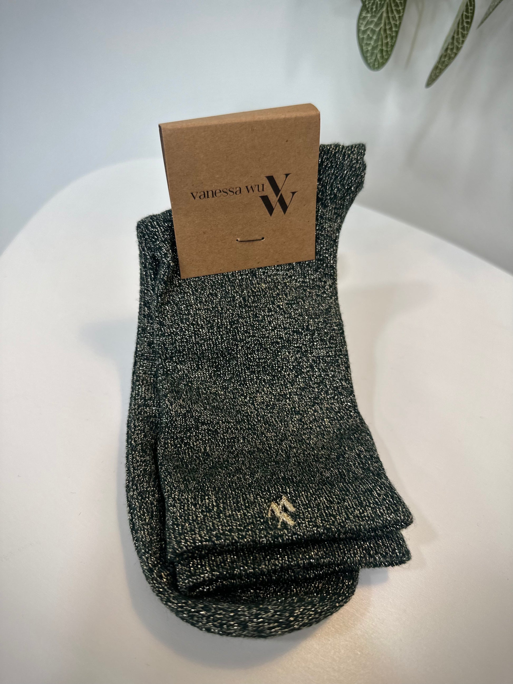 Paire de chaussettes vert foncé scintillantes posée sur fond clair