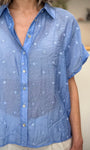 Détail broderies florales sur chemise bleue femme 