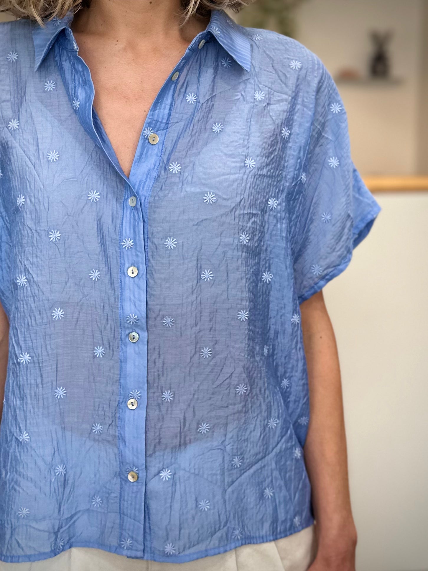 Détail broderies florales sur chemise bleue femme 