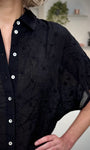 Détail broderies fleurs sur chemise noire femme 