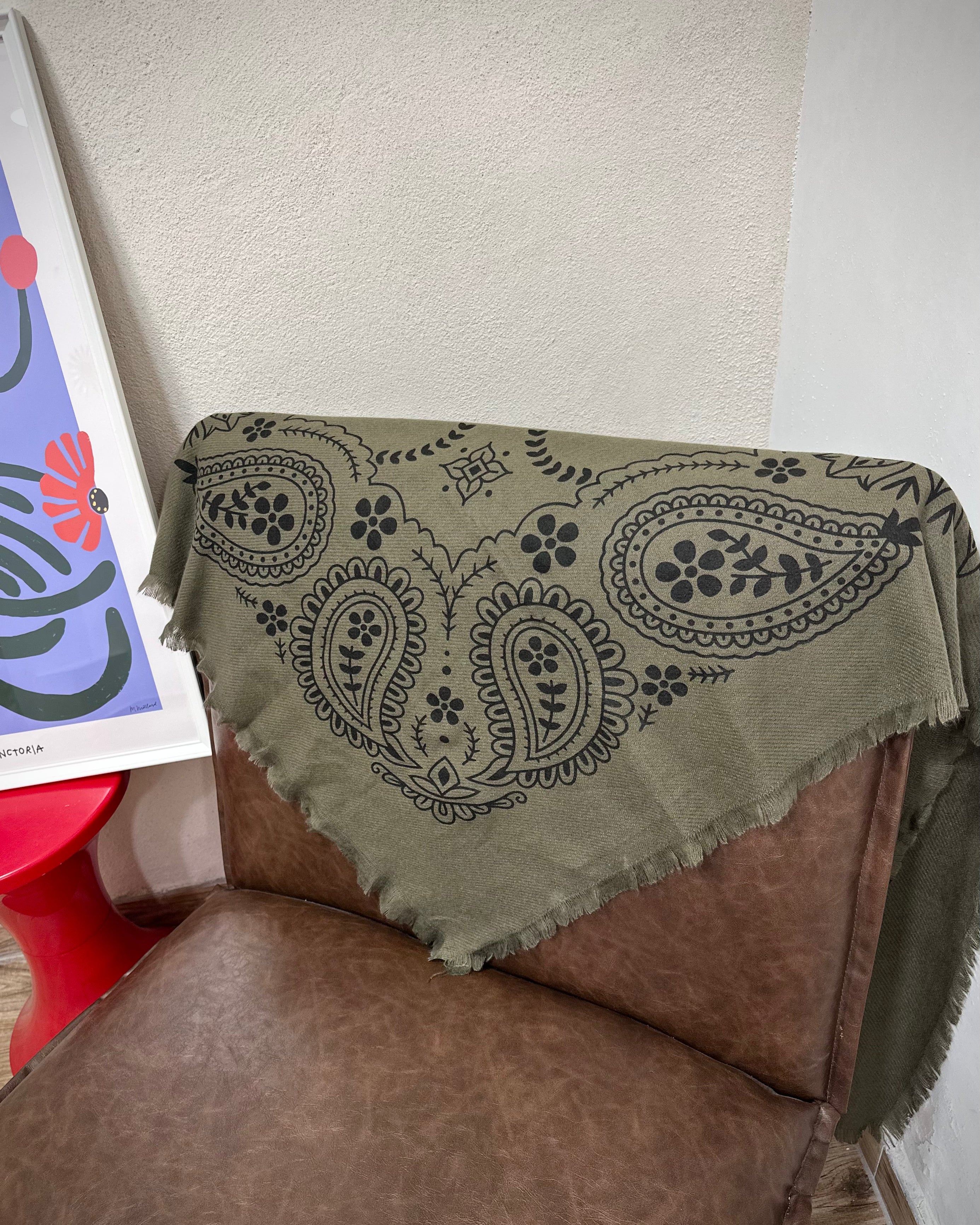 Echarpe kaki drapée sur un fauteuil marron