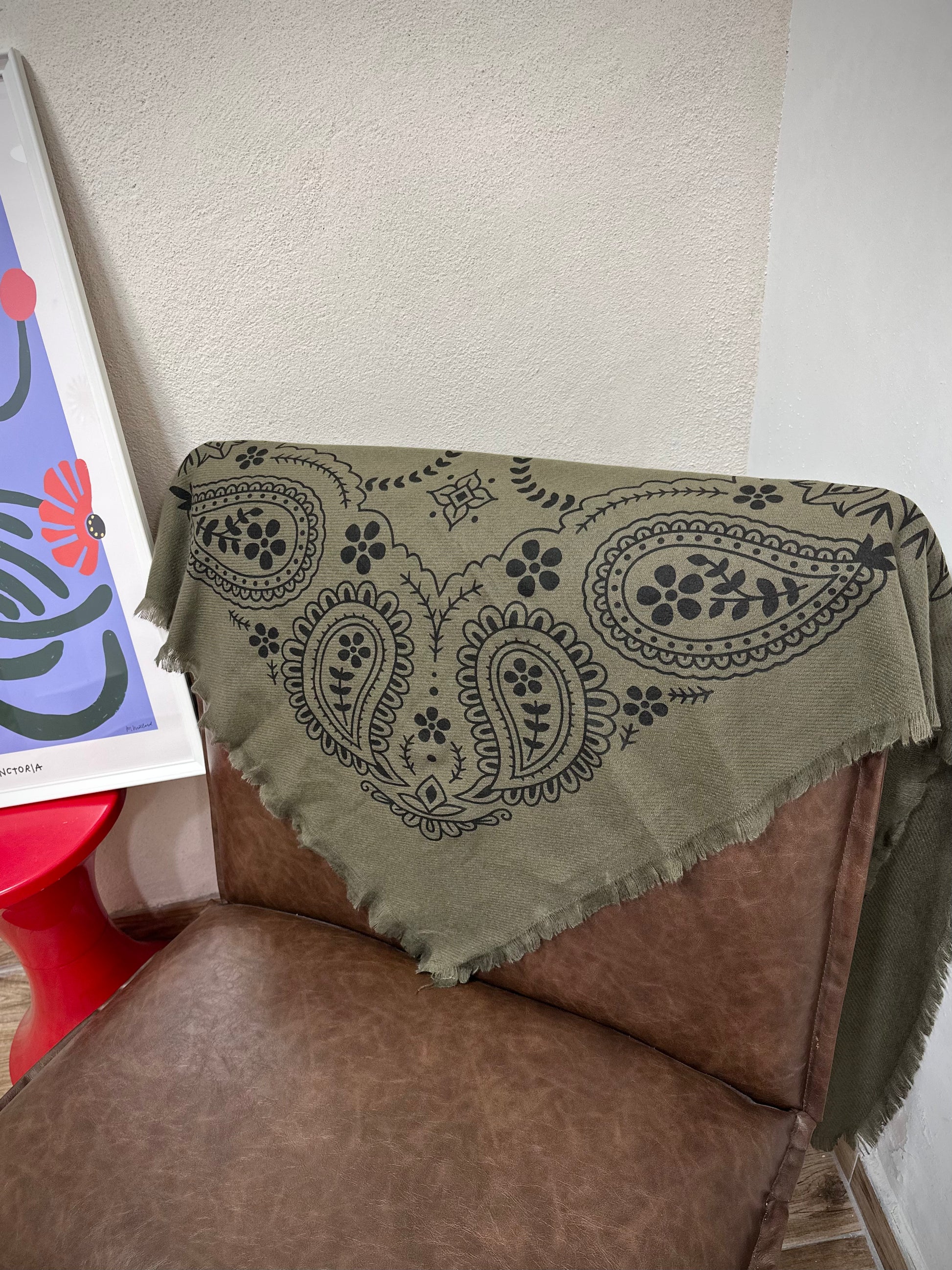 Echarpe kaki drapée sur un fauteuil marron