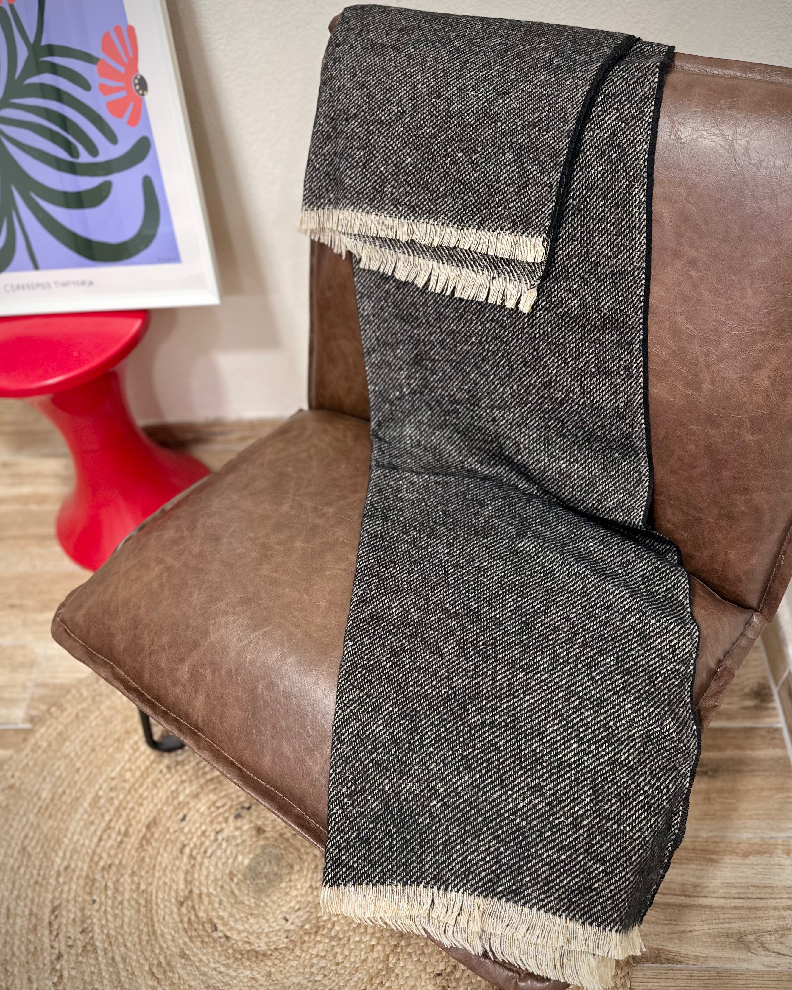 écharpe Mira noire dorée posée sur un fauteuil