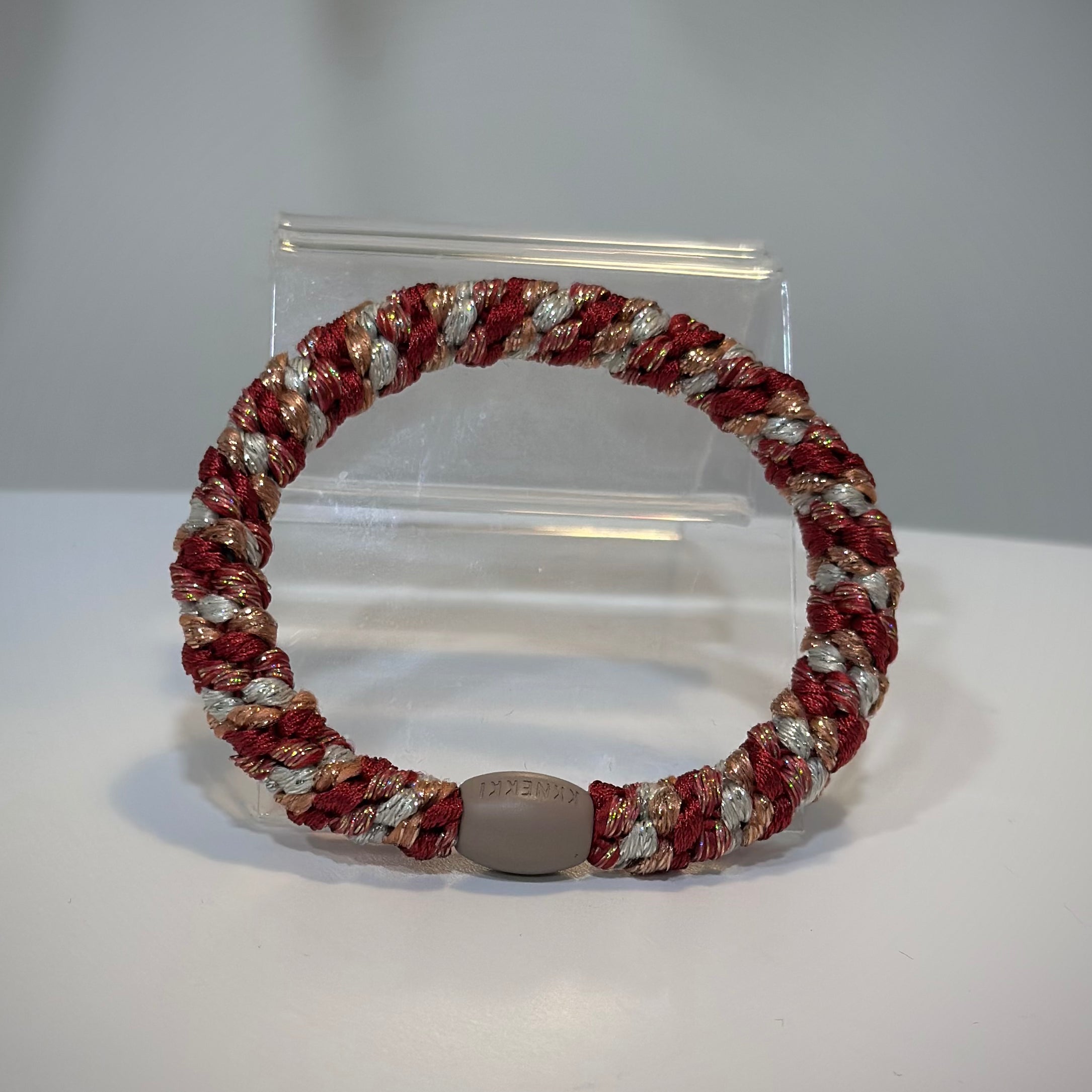 élastique Kknekki framboise pailleté posé sur table claire