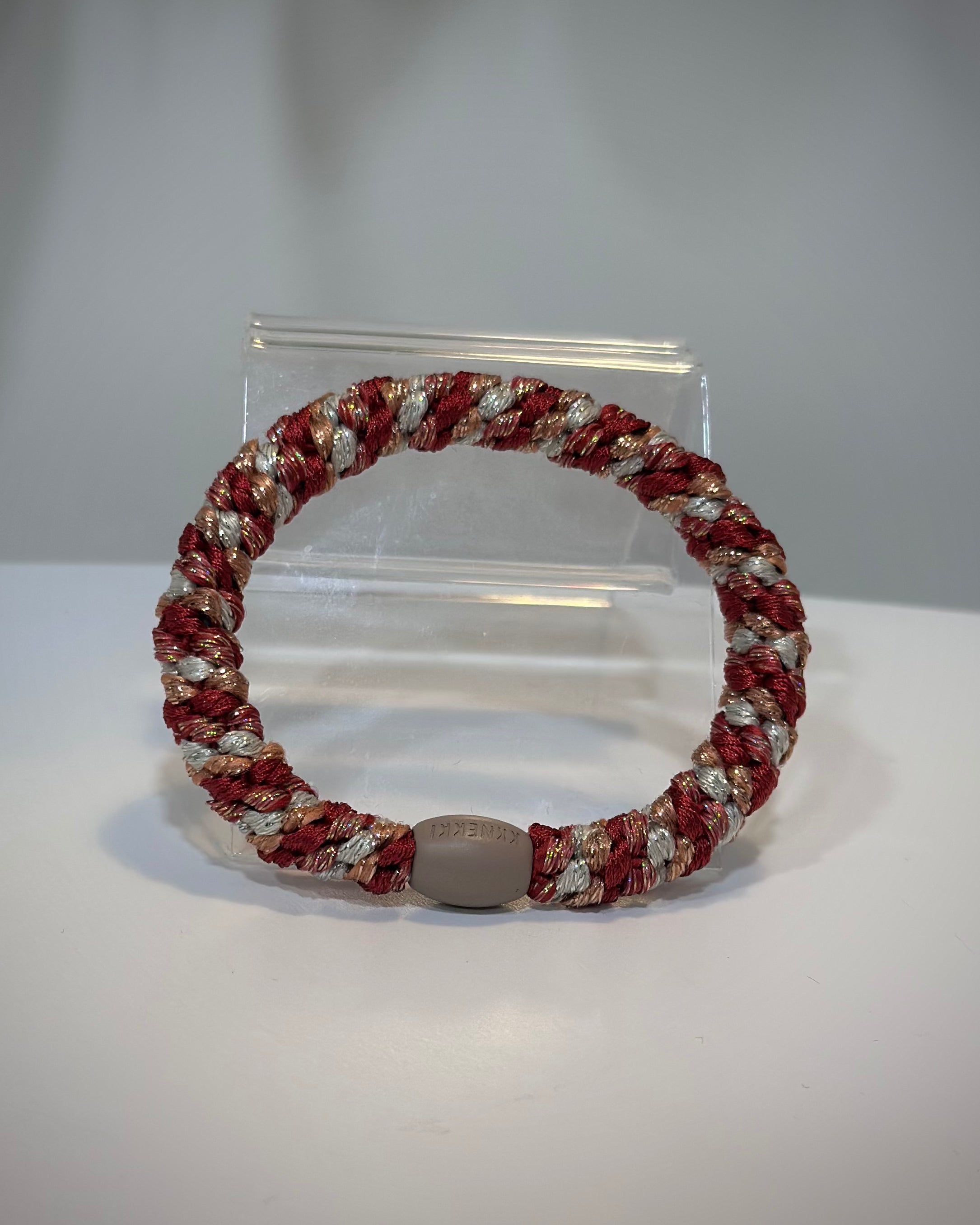 élastique Kknekki framboise pailleté posé sur table claire