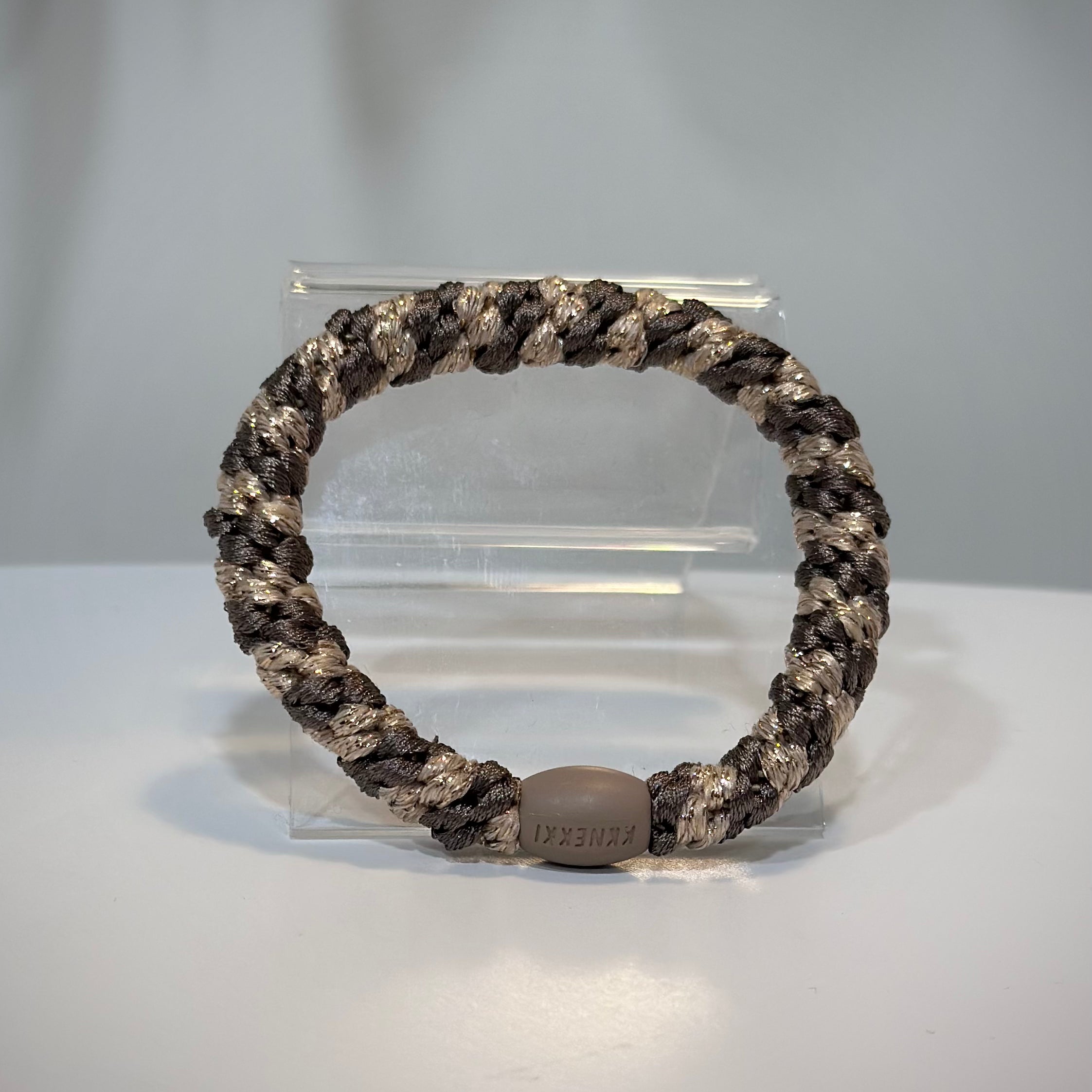 élastique Kknekki moka beige pailleté posé sur table en bois clair