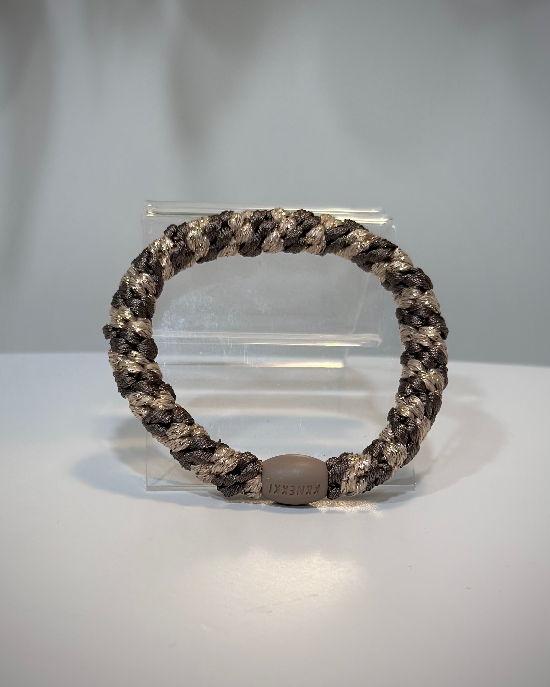 élastique Kknekki moka beige pailleté posé sur table en bois clair