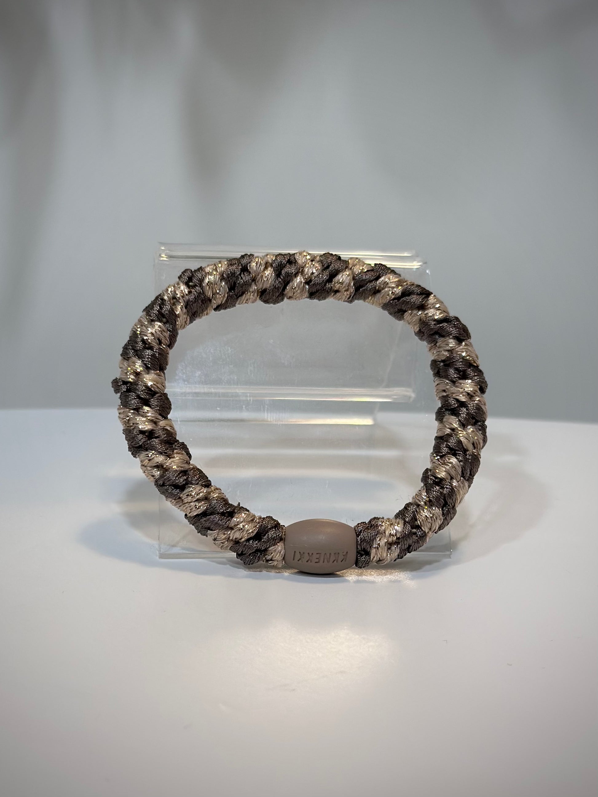 élastique Kknekki moka beige pailleté posé sur table en bois clair