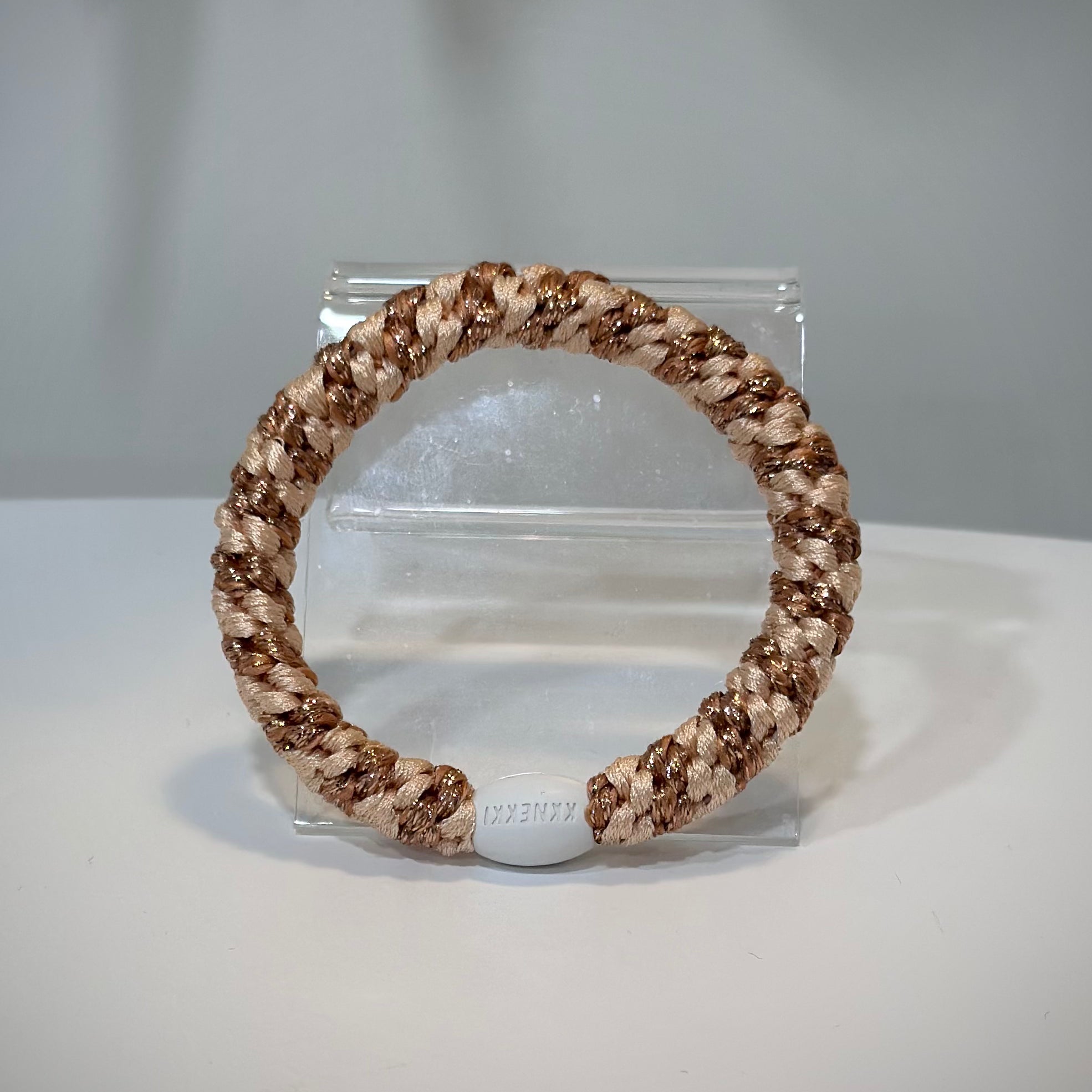 élastiques Kknekki rose gold et orange posés sur une table claire