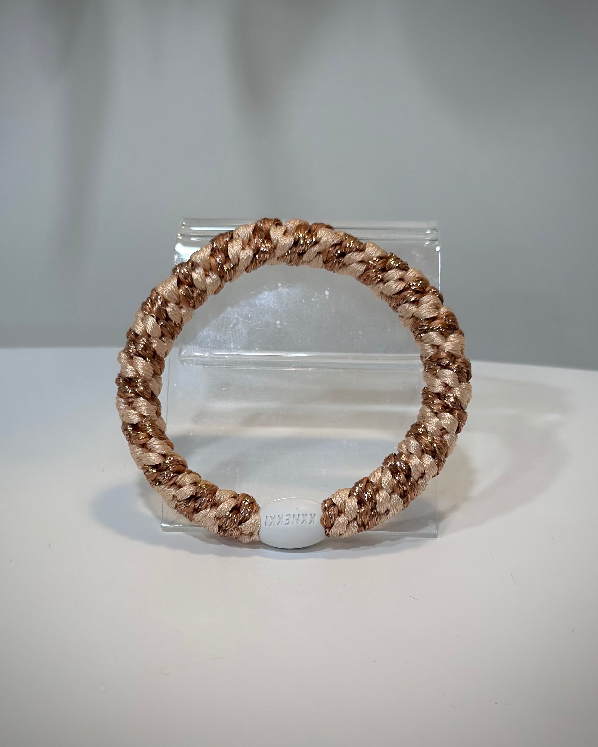 élastiques Kknekki rose gold et orange posés sur une table claire