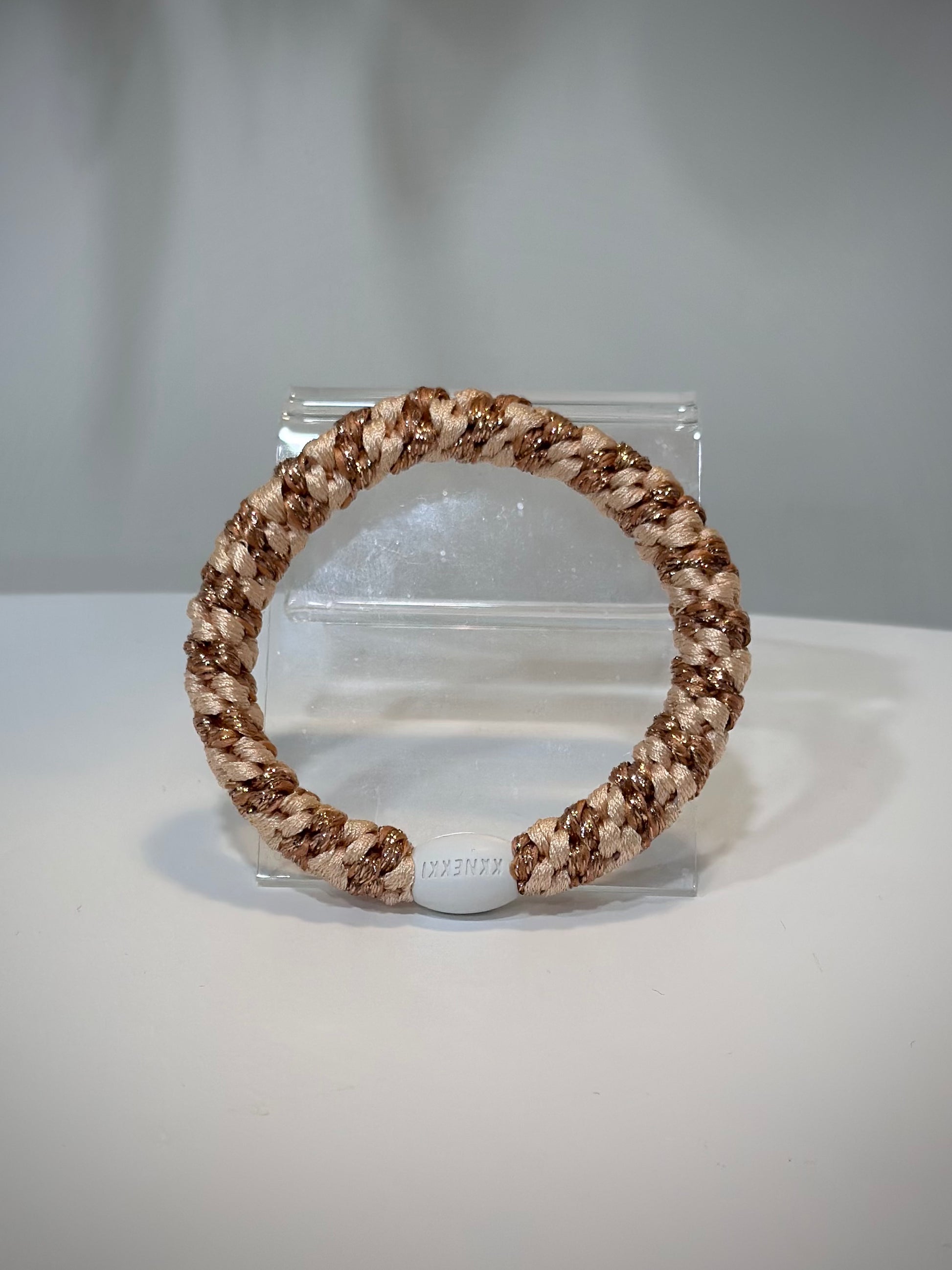 élastiques Kknekki rose gold et orange posés sur une table claire