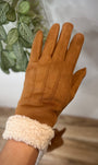 Gants camel élégants portés devant une plante