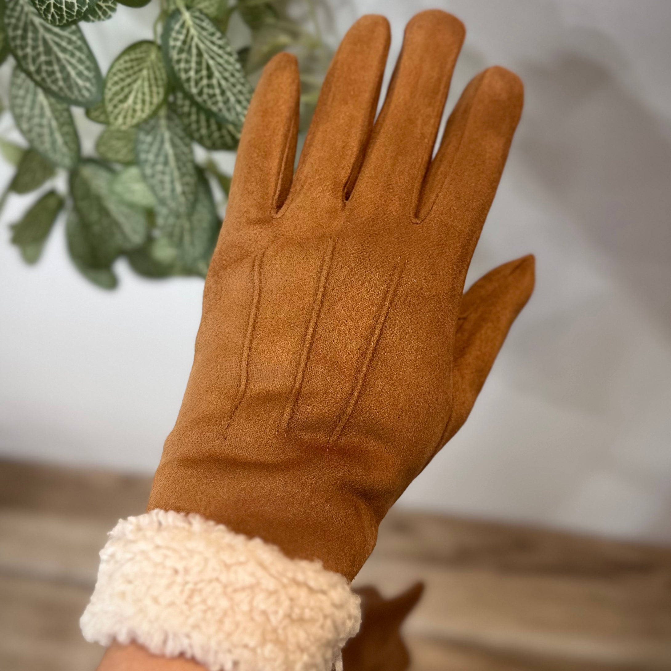 Gants camel élégants portés devant une plante