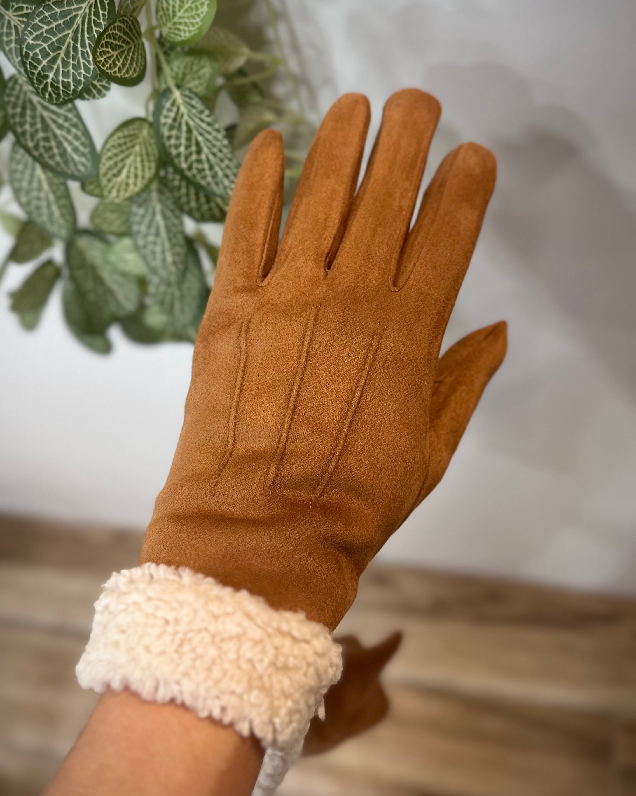 Gants camel élégants portés devant une plante