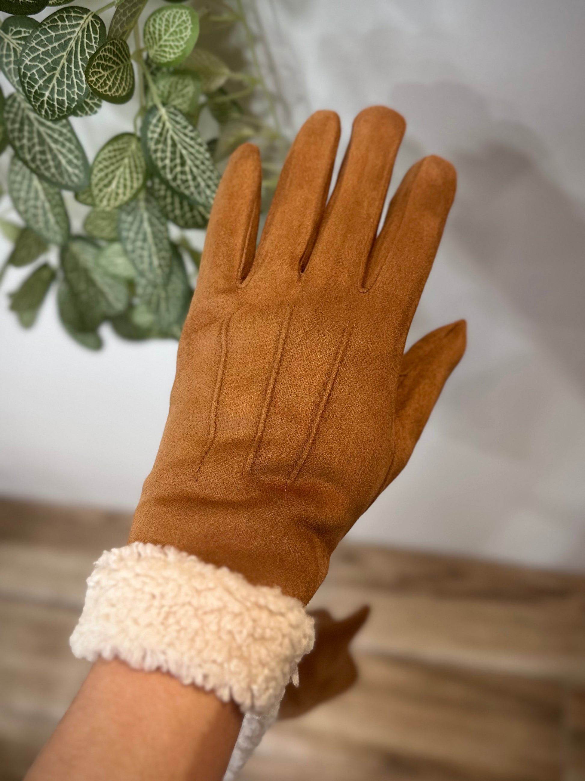 Gants camel élégants portés devant une plante