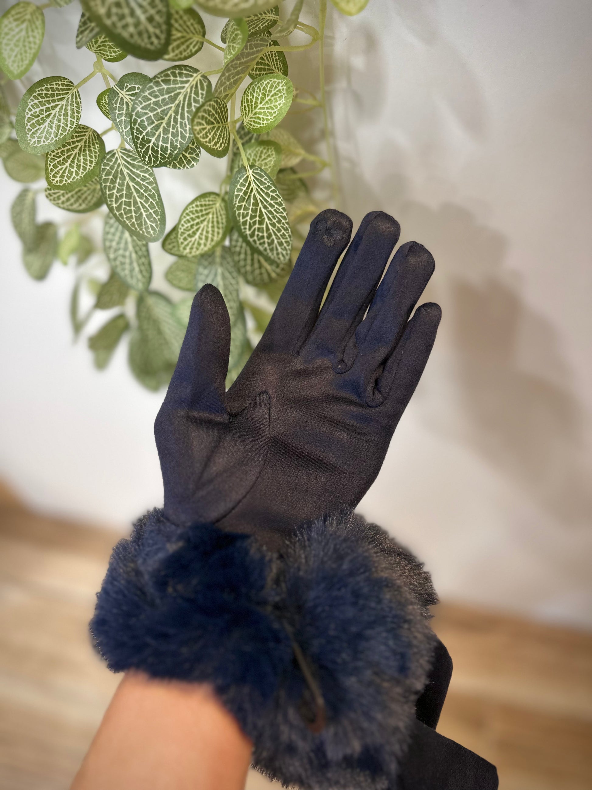 Gants bleu marine portés devant un mur clair