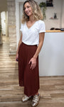 Tenue casual chic avec jupe plissée chocolat et baskets dorées