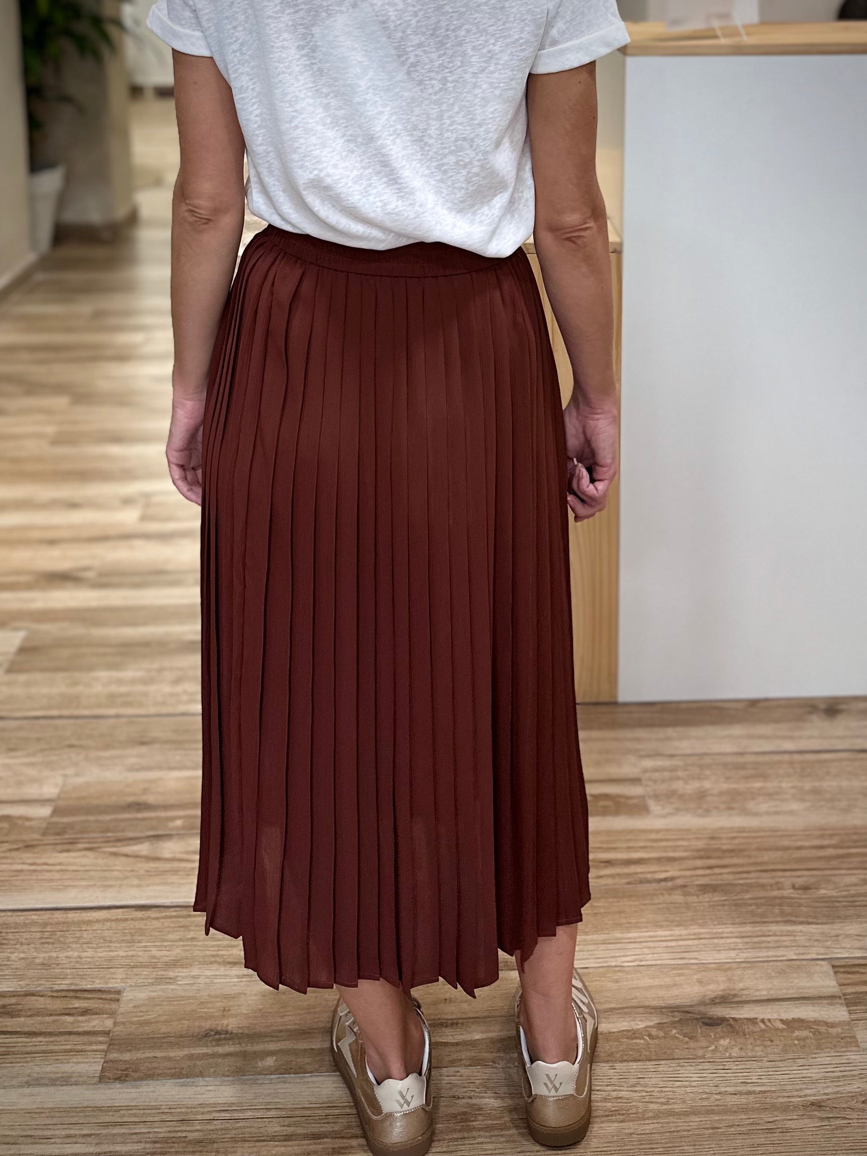 Silhouette féminine de dos avec jupe plissée fluide couleur chocolat