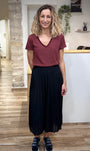 Look casual chic avec jupe noire plissée et baskets 
