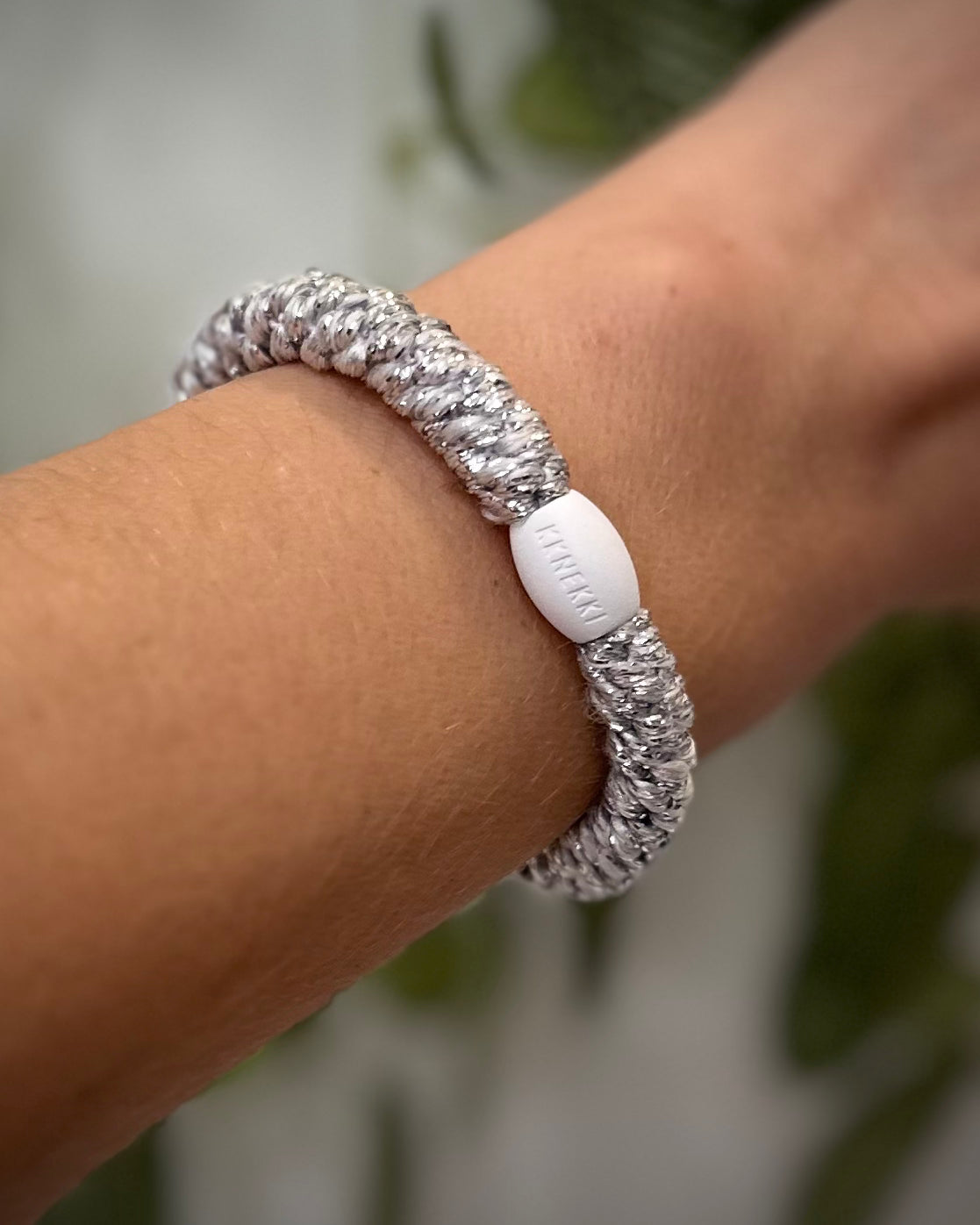 Elastique Kknekki argent métallisé porté comme bracelet sur poignet femme