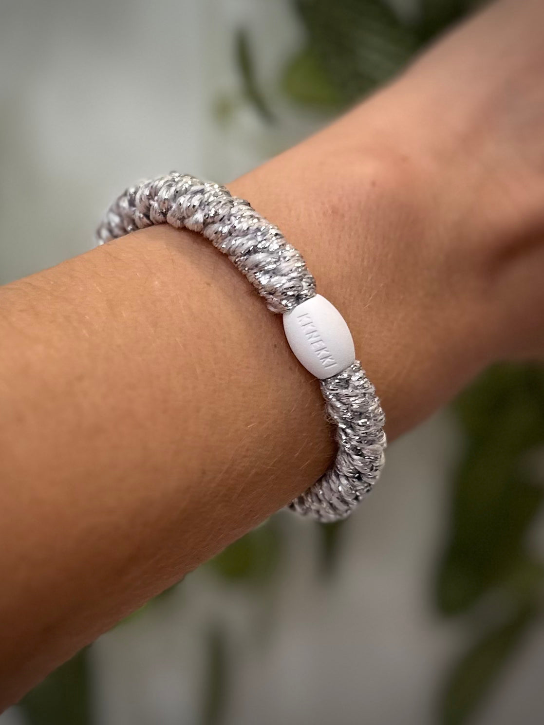 Elastique Kknekki argent métallisé porté comme bracelet sur poignet femme